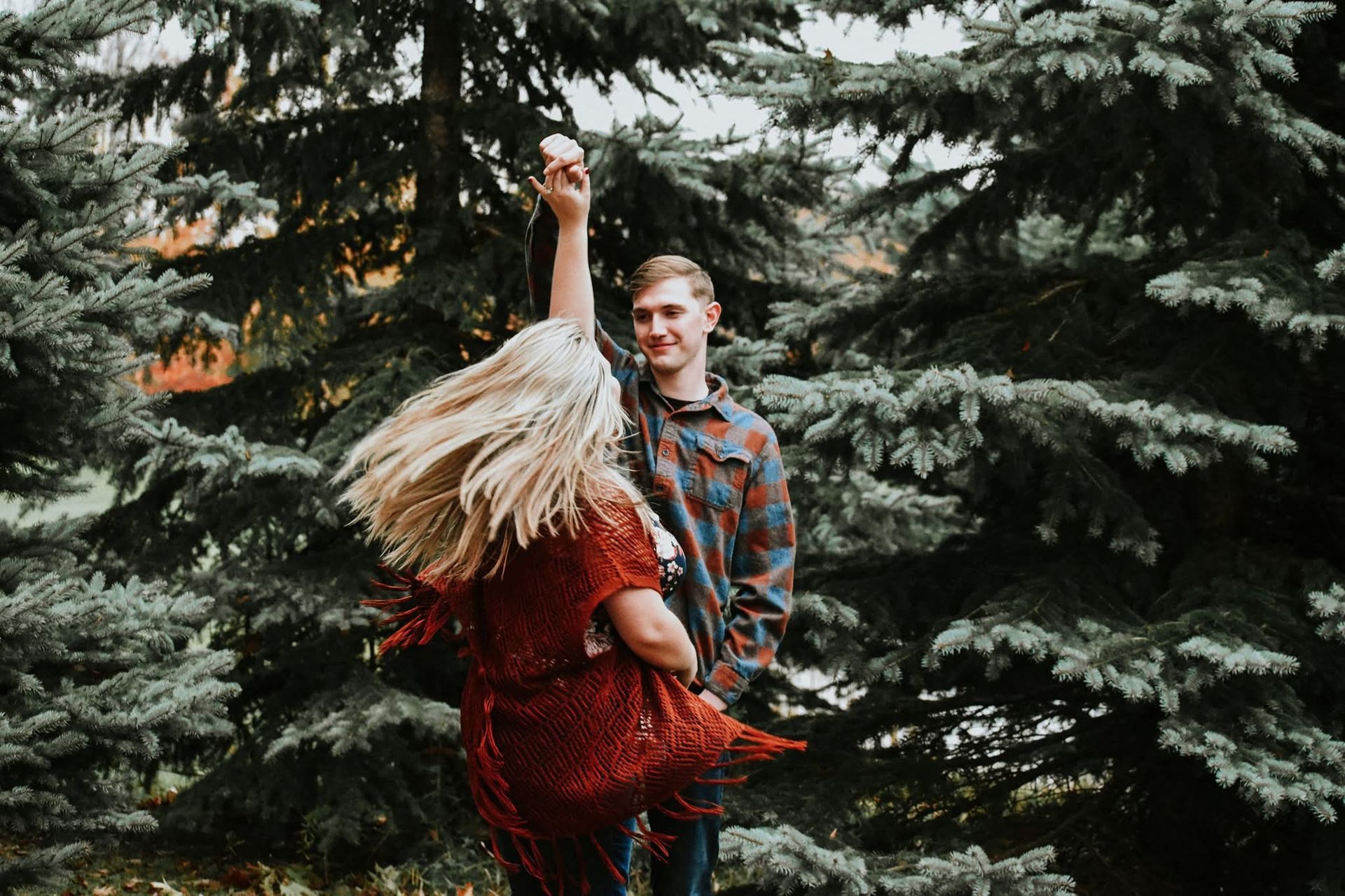 A man and a woman are dancing in the woods.