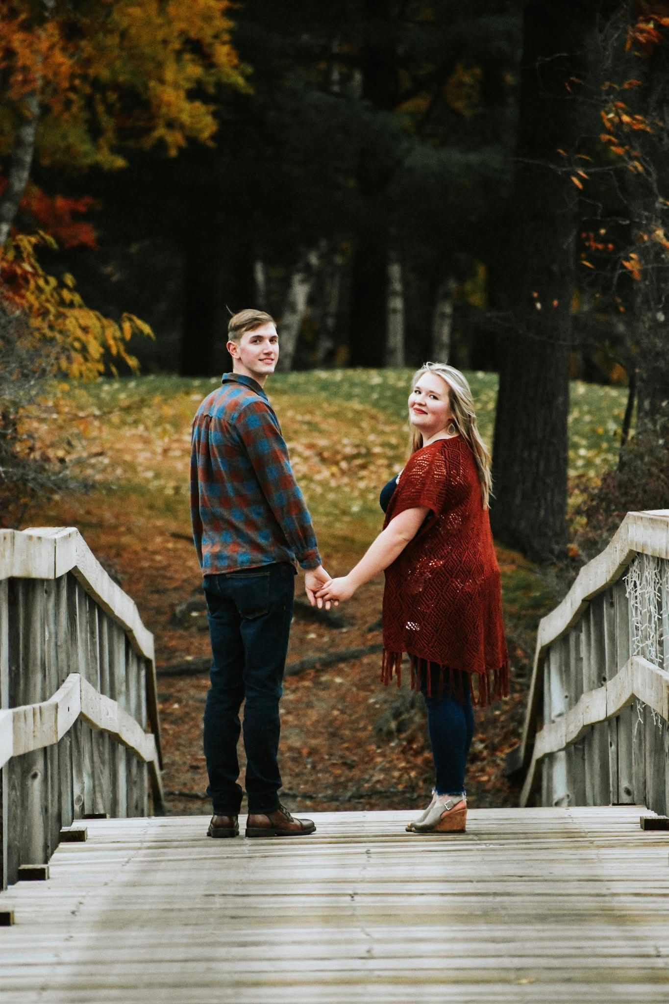 A man and a woman are holding hands on a wooden bridge.