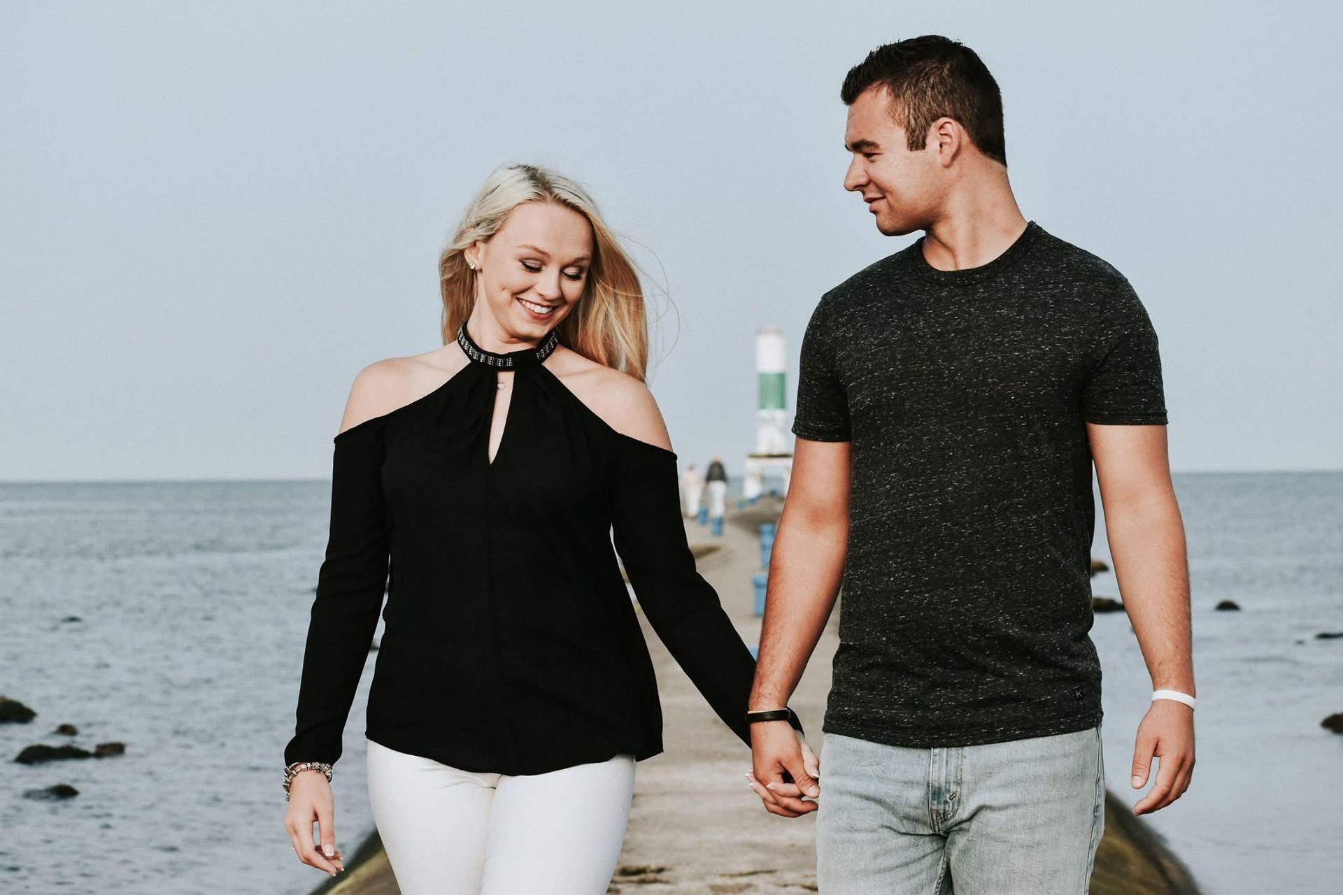 A man and a woman are holding hands while walking on a pier.
