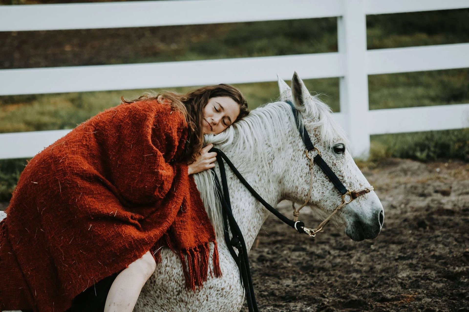 A woman is riding on the back of a white horse.
