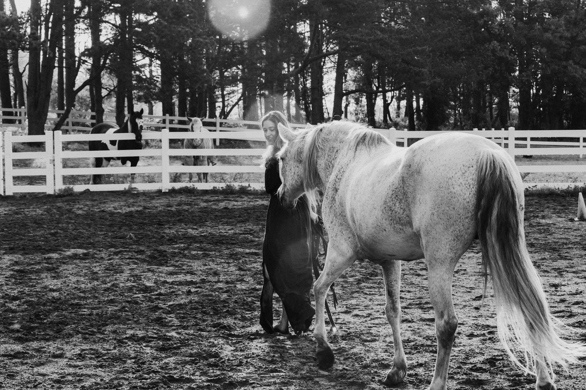 A black and white photo of a man standing next to a horse