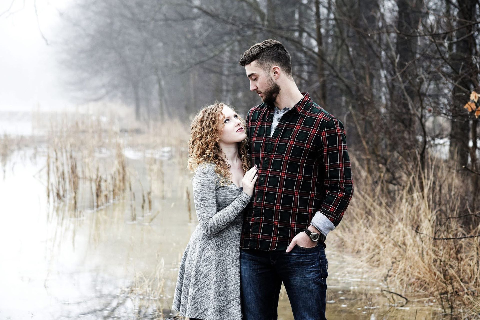 A man and a woman are standing next to each other in front of a body of water.