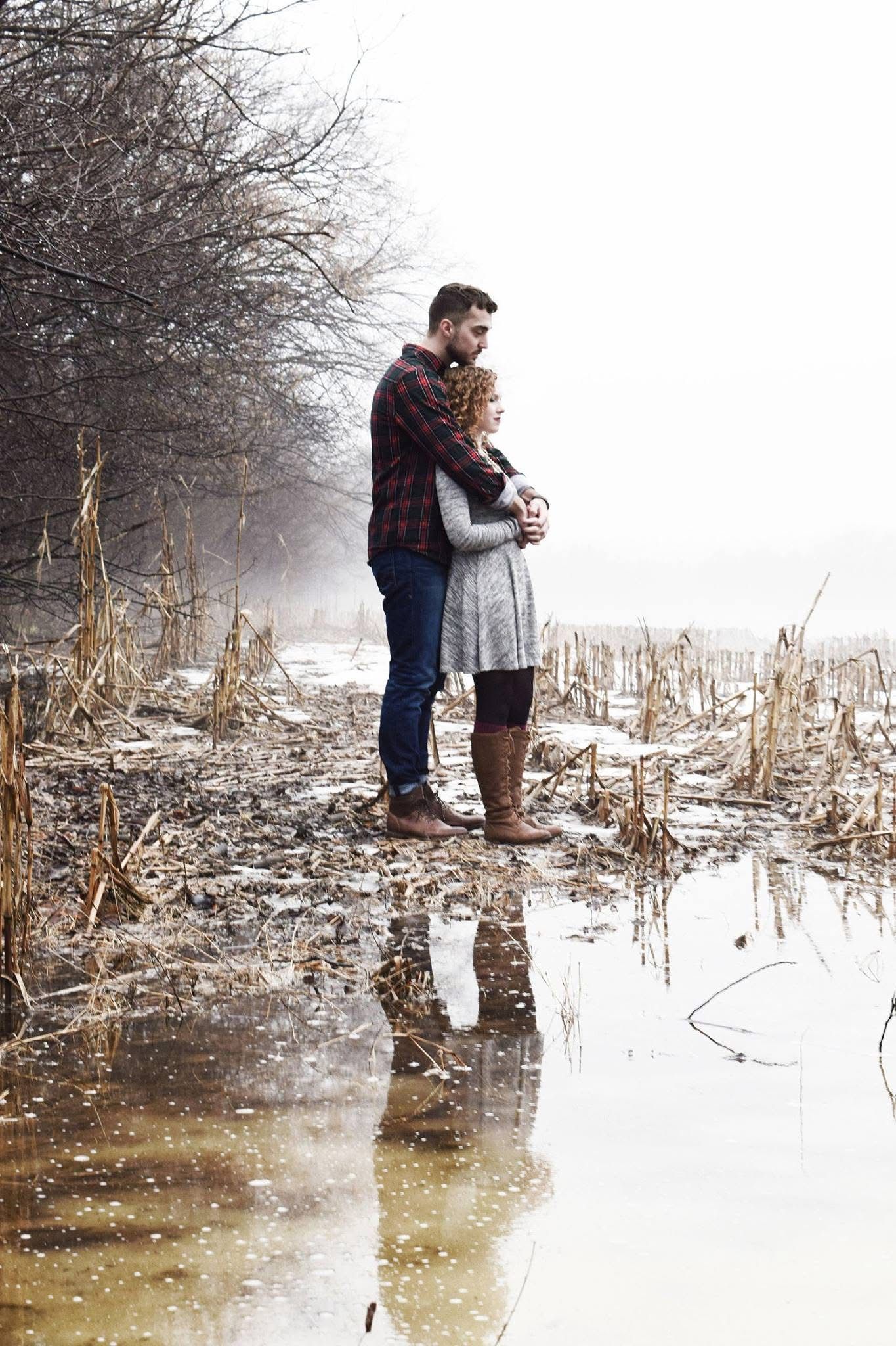 A man and a woman are hugging in a puddle of water.