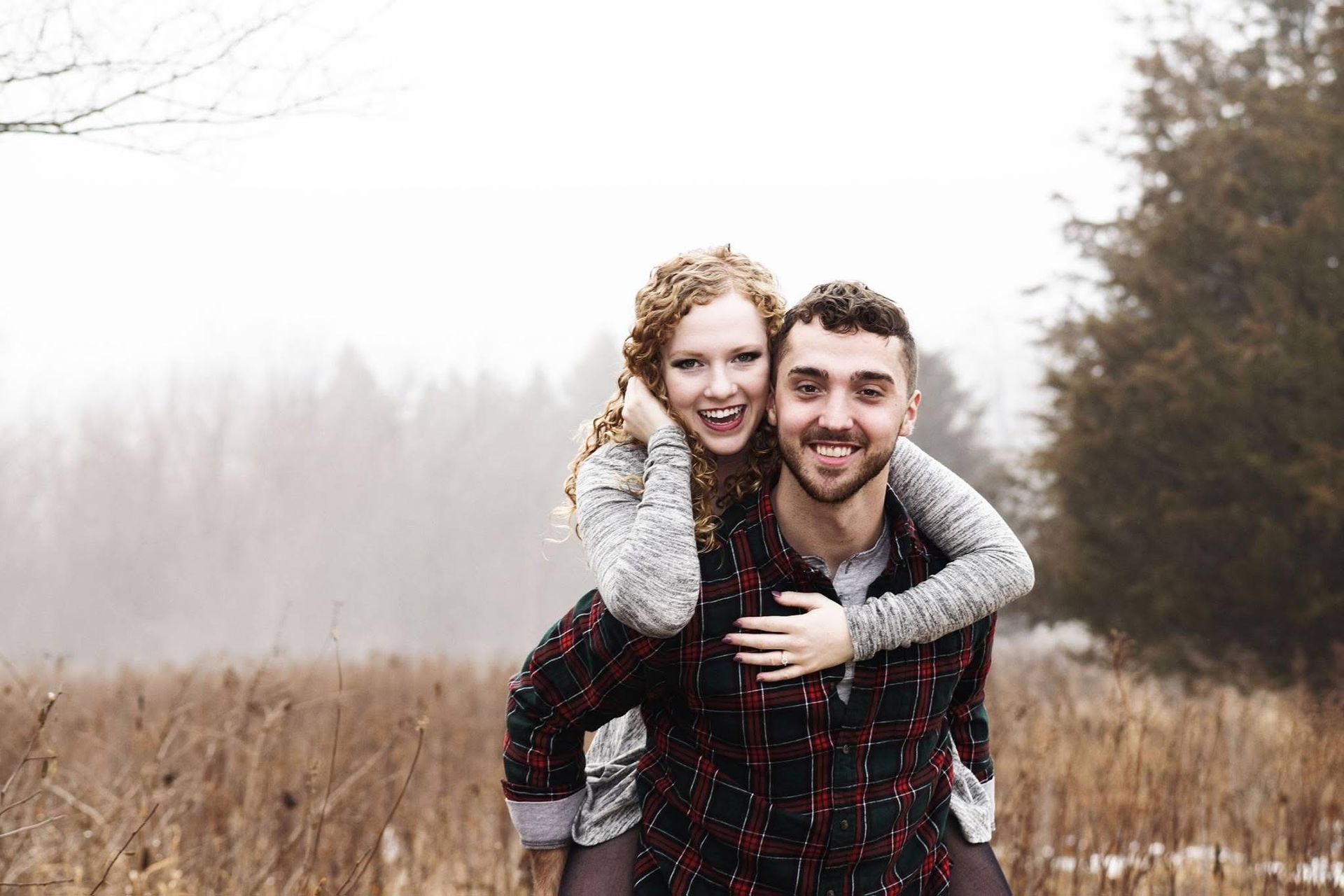 A man is carrying a woman on his back in a field.