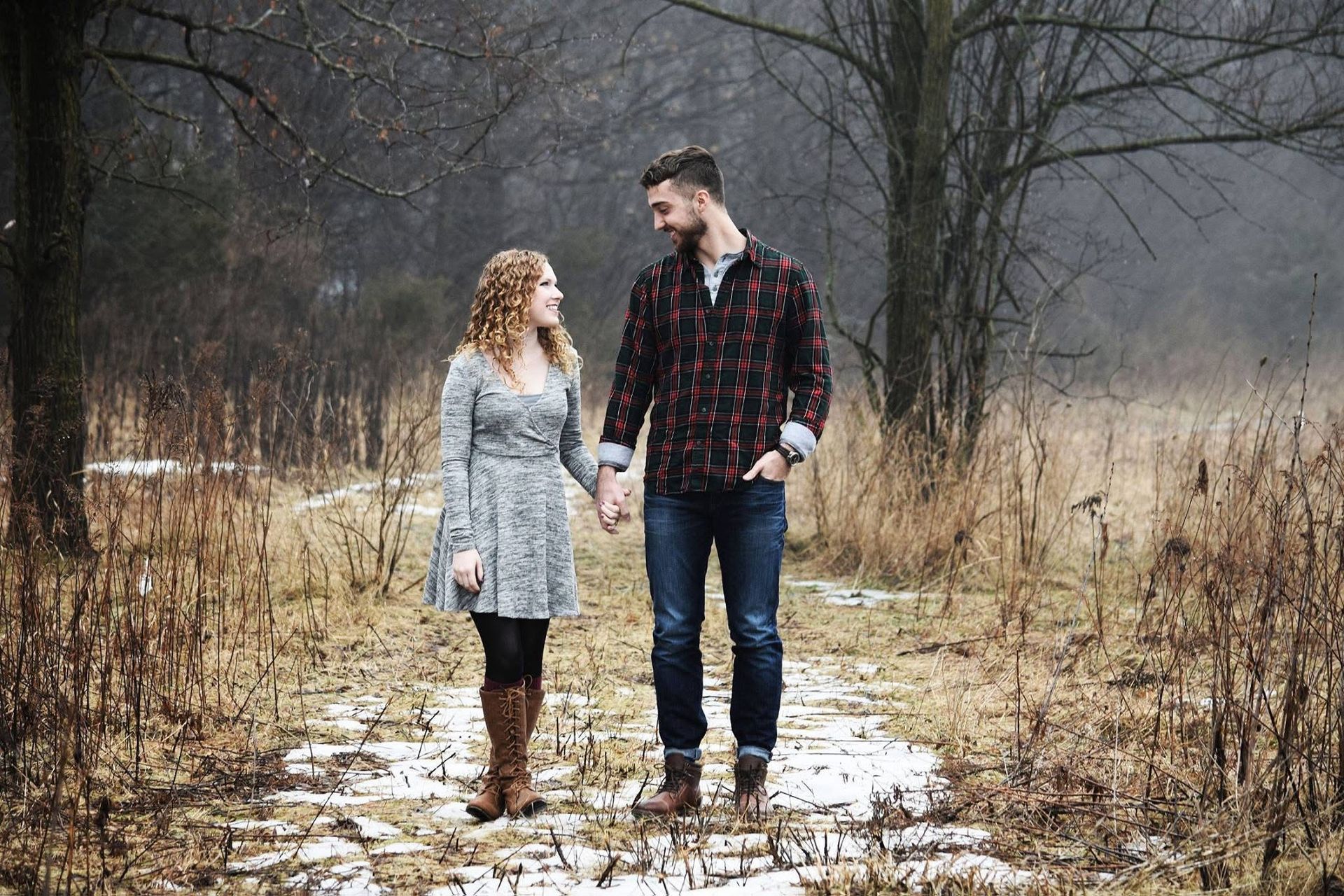 A man and a woman are holding hands while walking through a field.