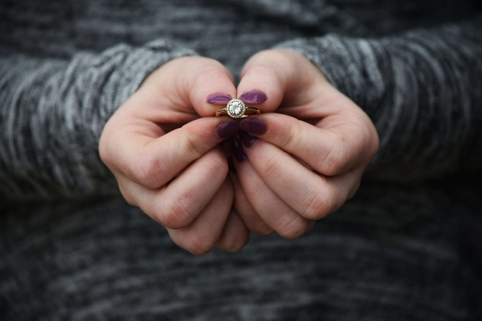 A woman is holding a diamond ring in her hands.