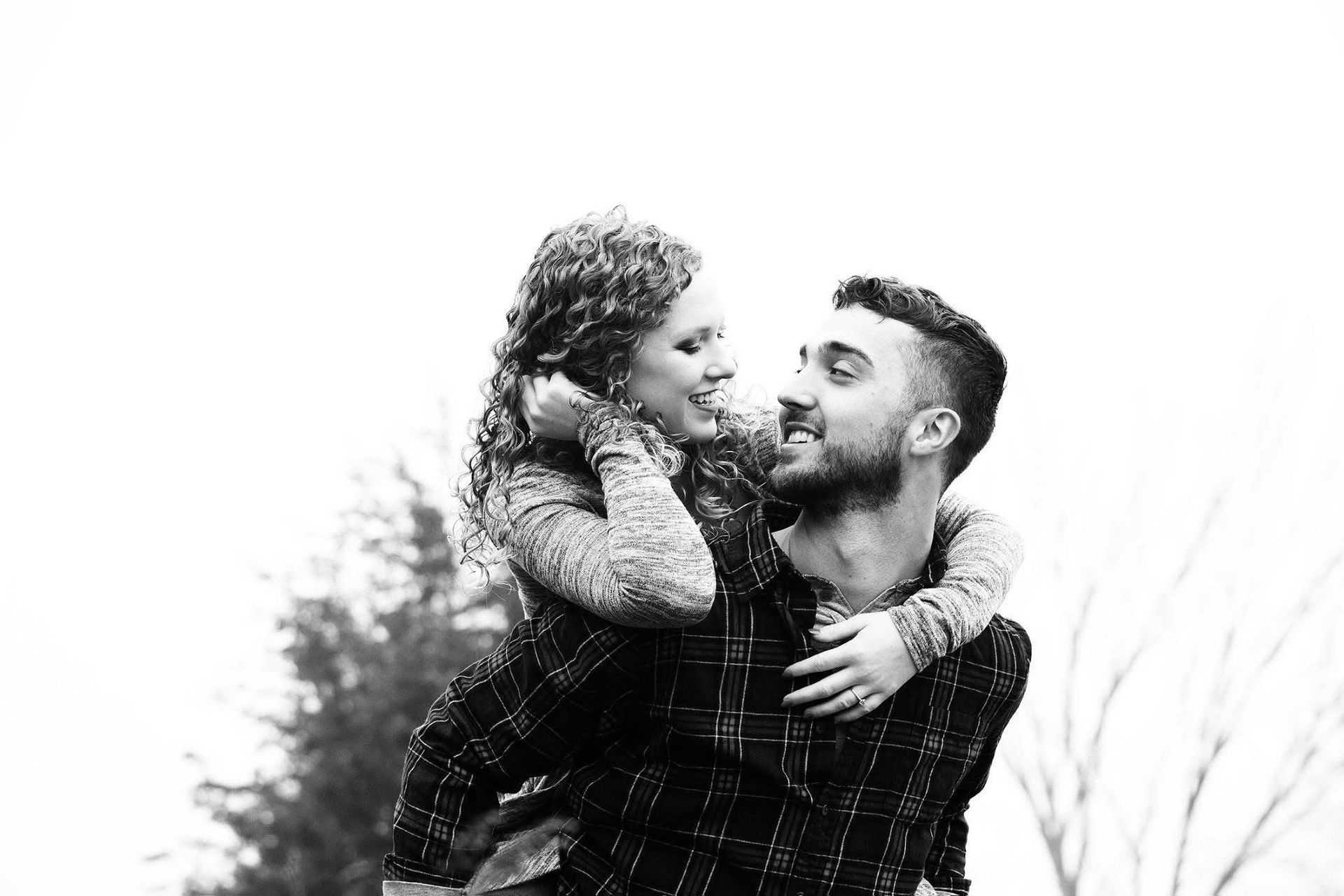 A man is carrying a woman on his back in a black and white photo.