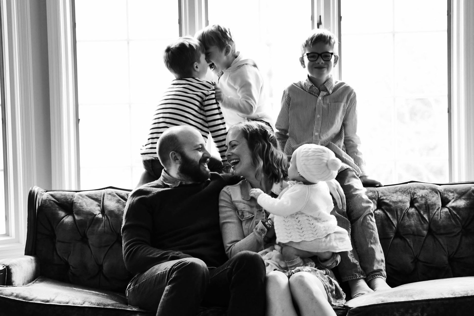 A black and white photo of a family sitting on a couch.