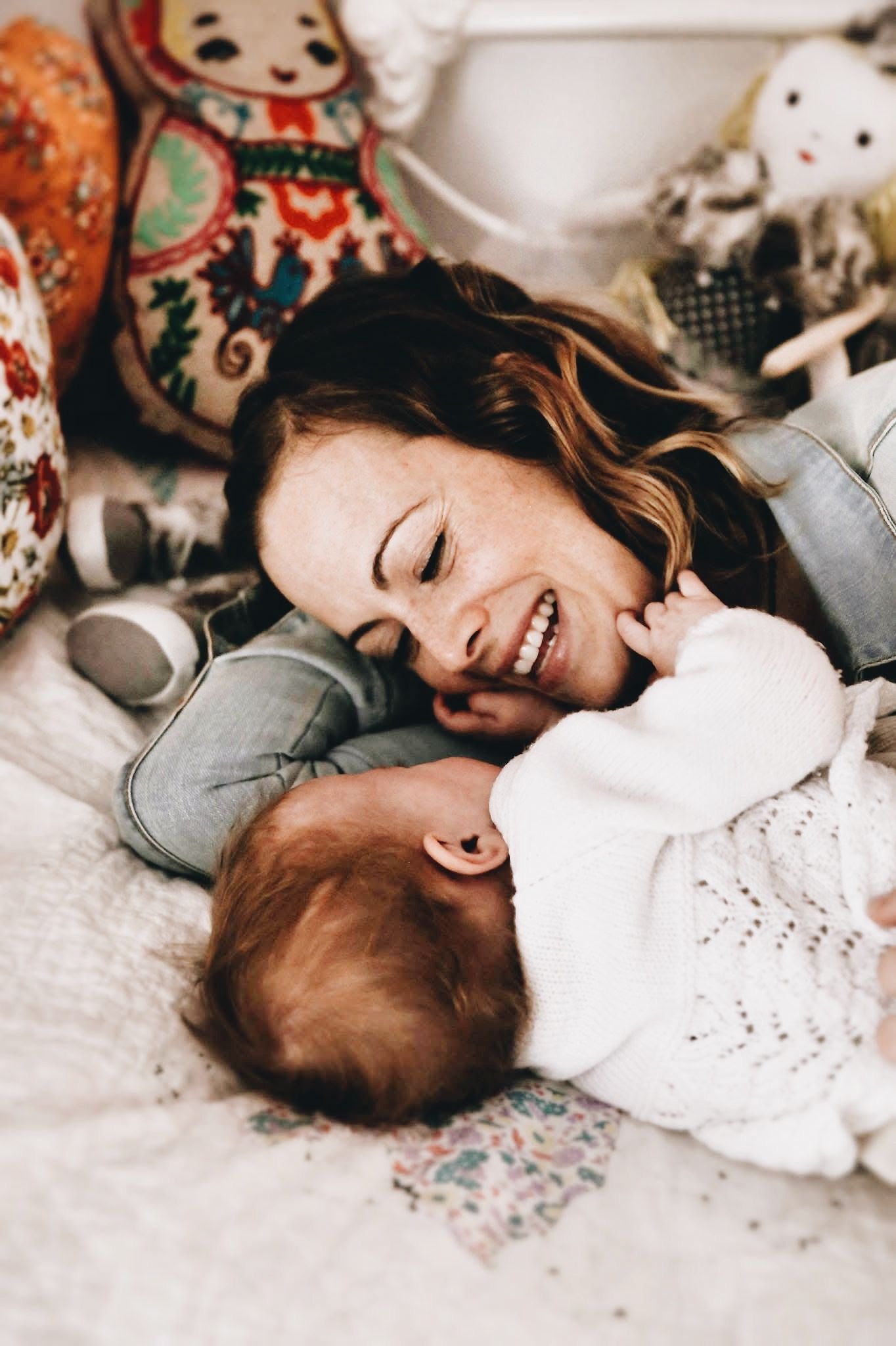 A woman is laying on a bed with a baby.