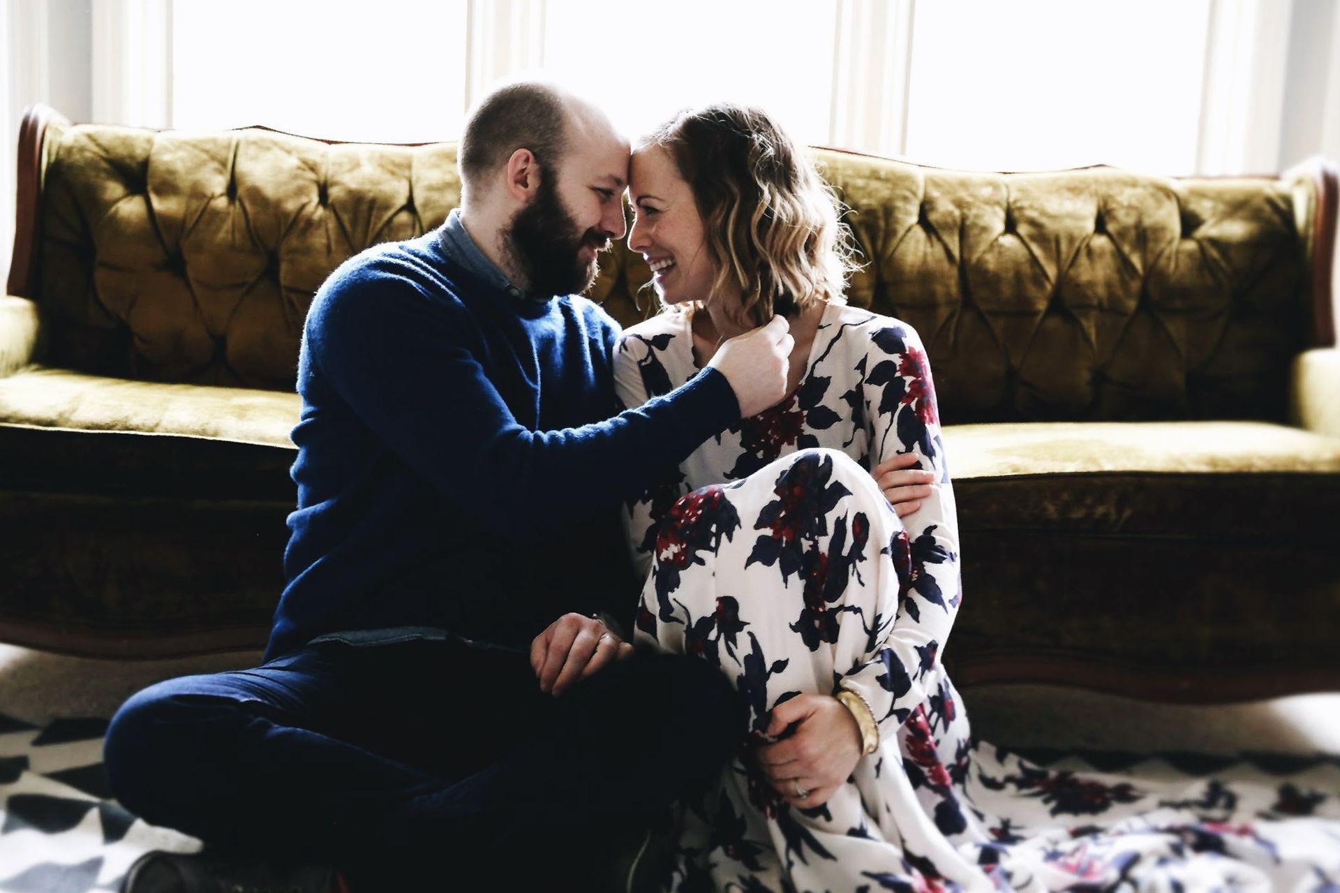 A man and a woman are sitting on the floor in front of a couch.