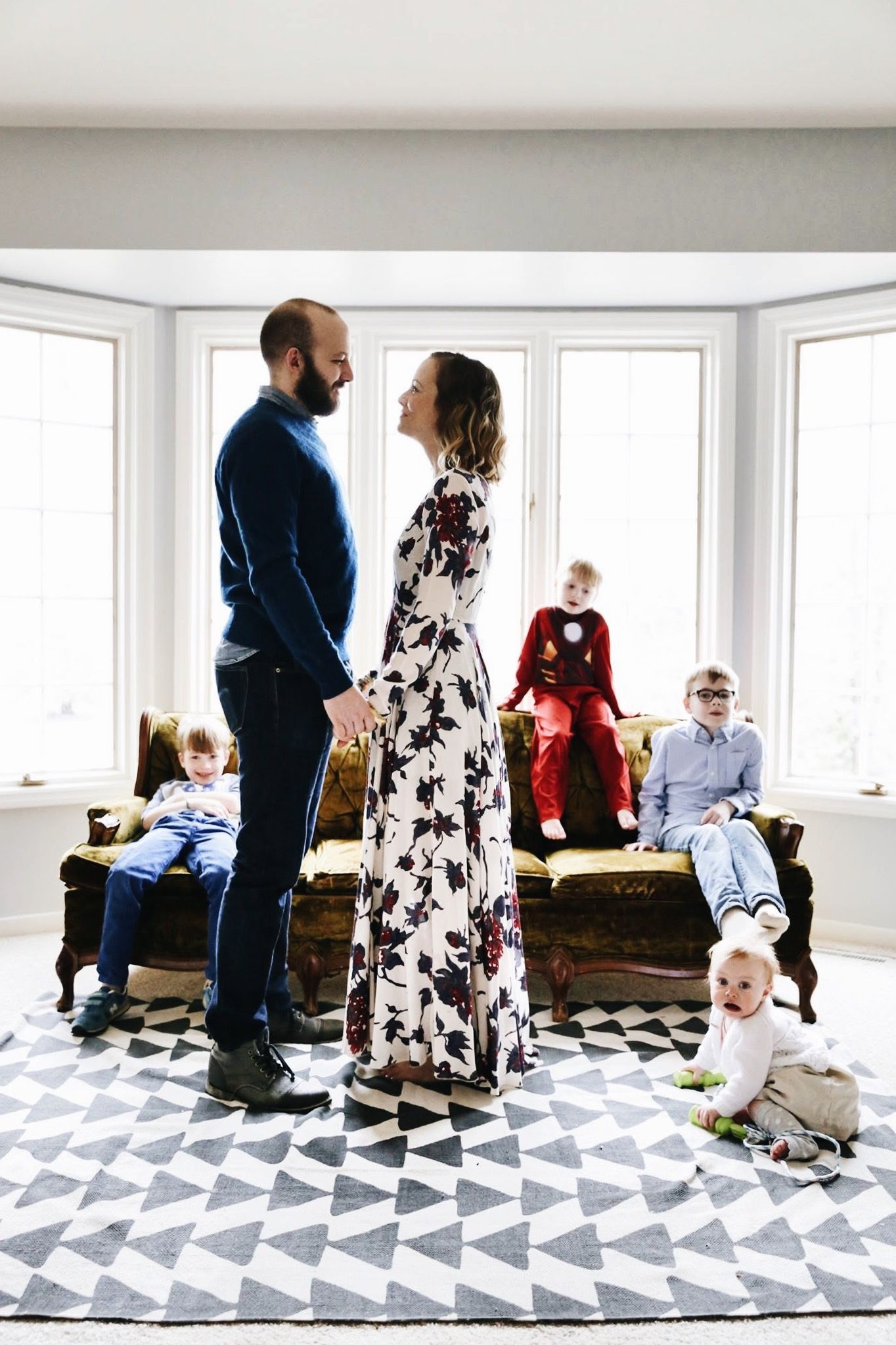 A family is standing in a living room holding hands.
