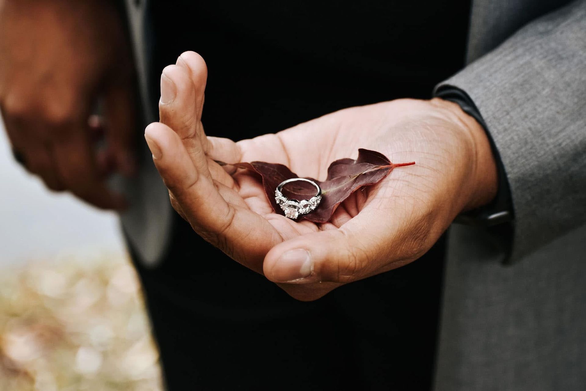 A man is holding a ring and a leaf in his hands.