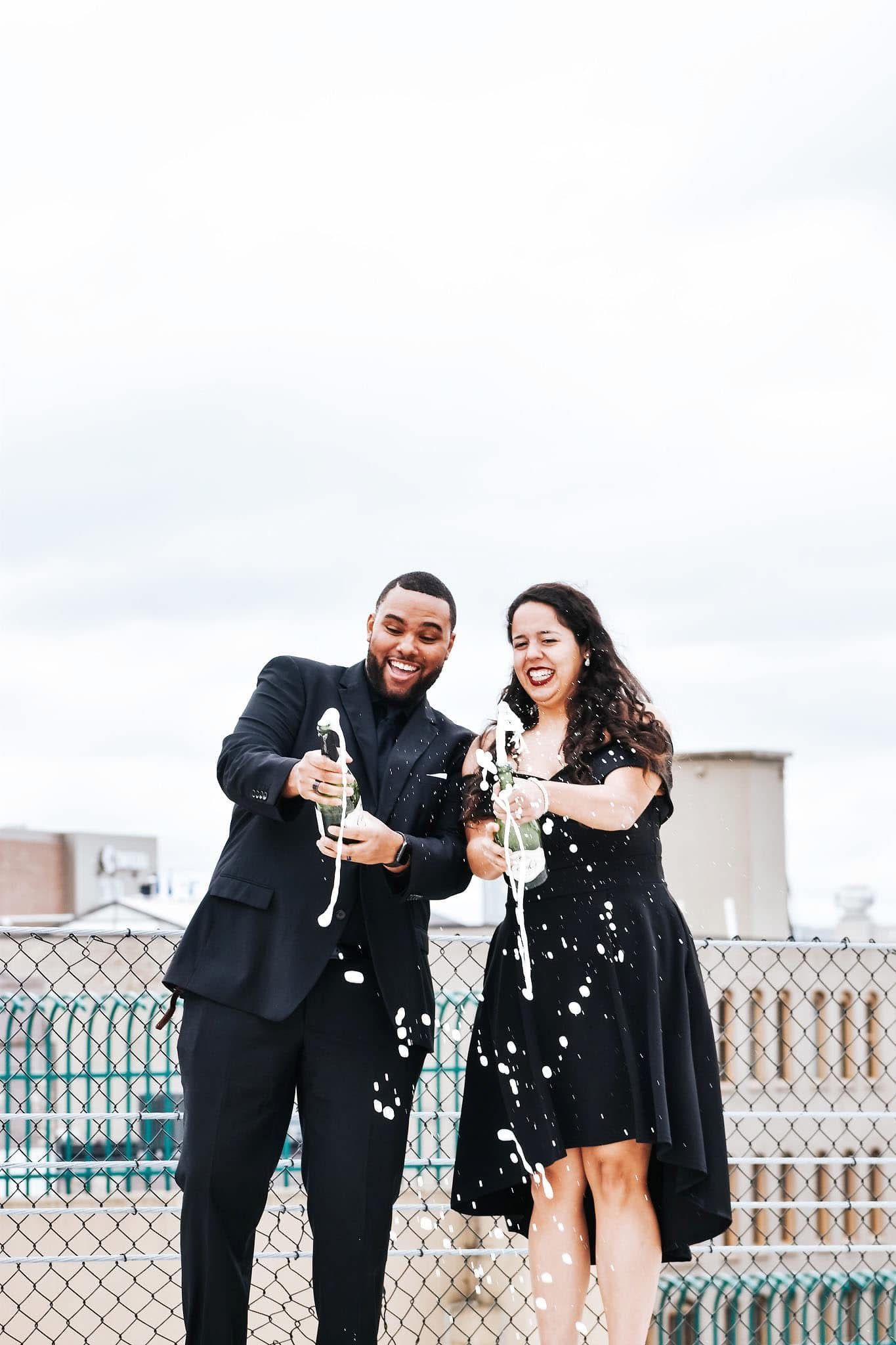 A man and a woman are holding champagne glasses and throwing confetti.