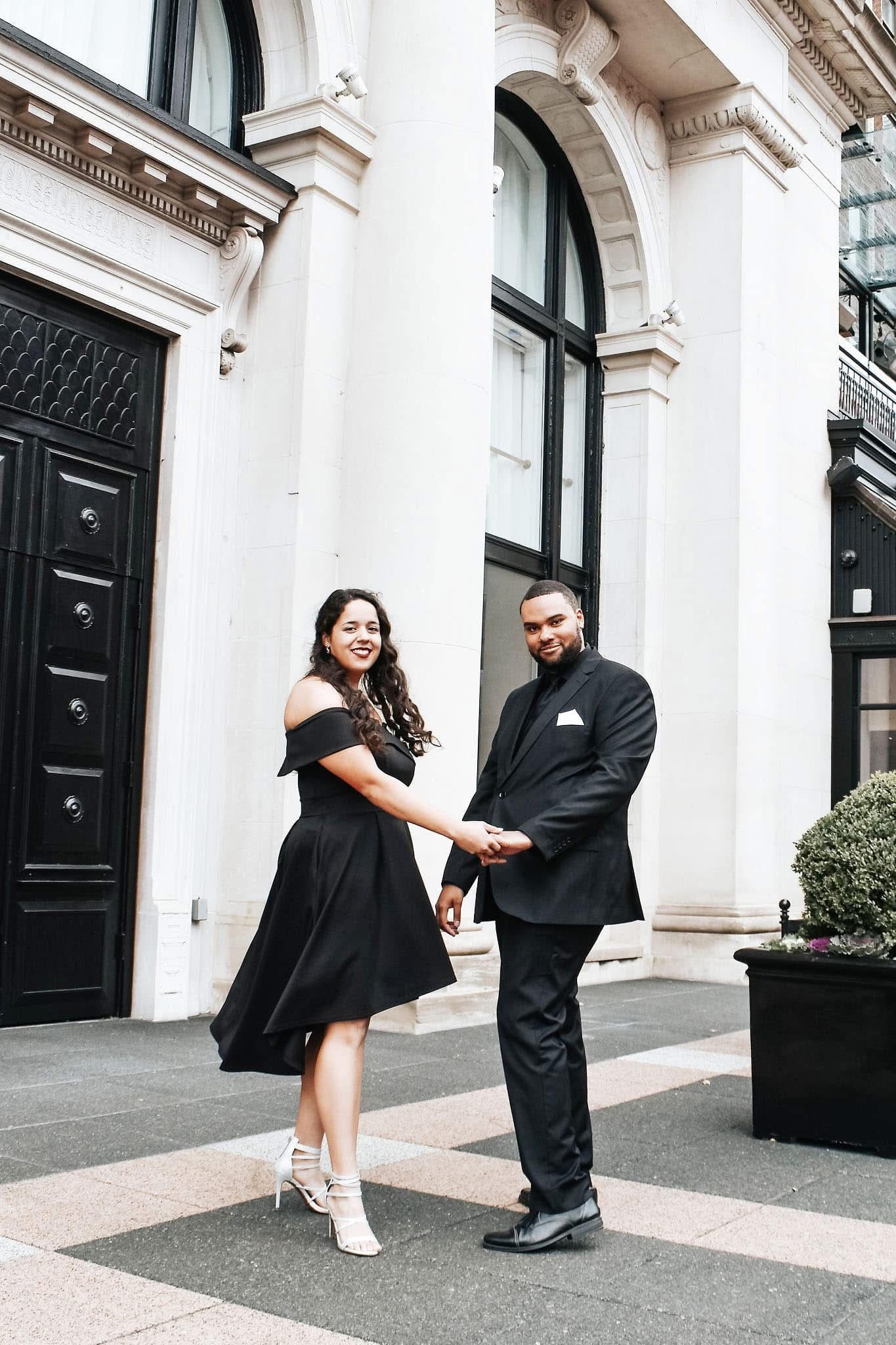 A man and a woman are holding hands in front of a building.