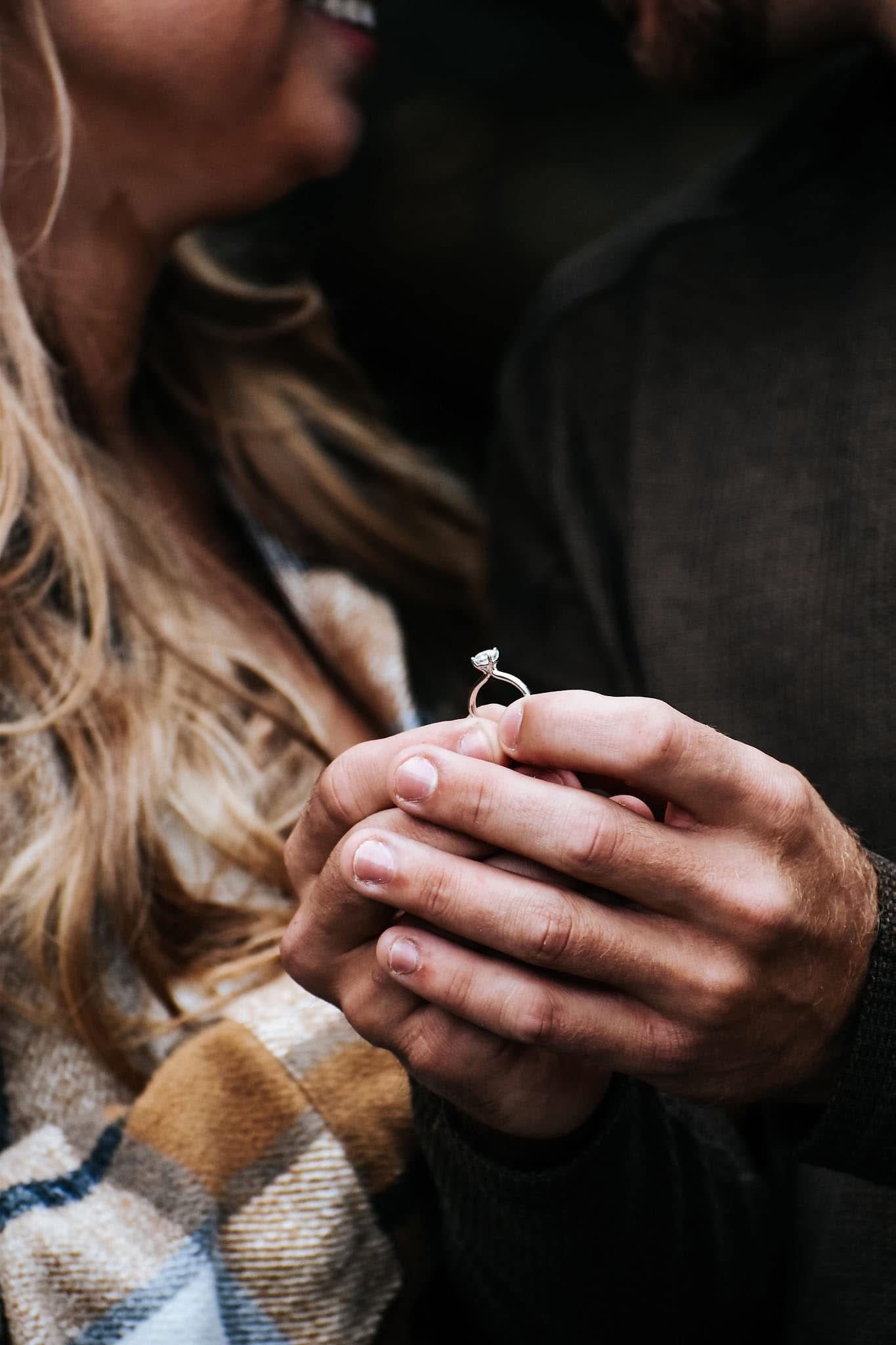 A man is putting an engagement ring on a woman 's finger.