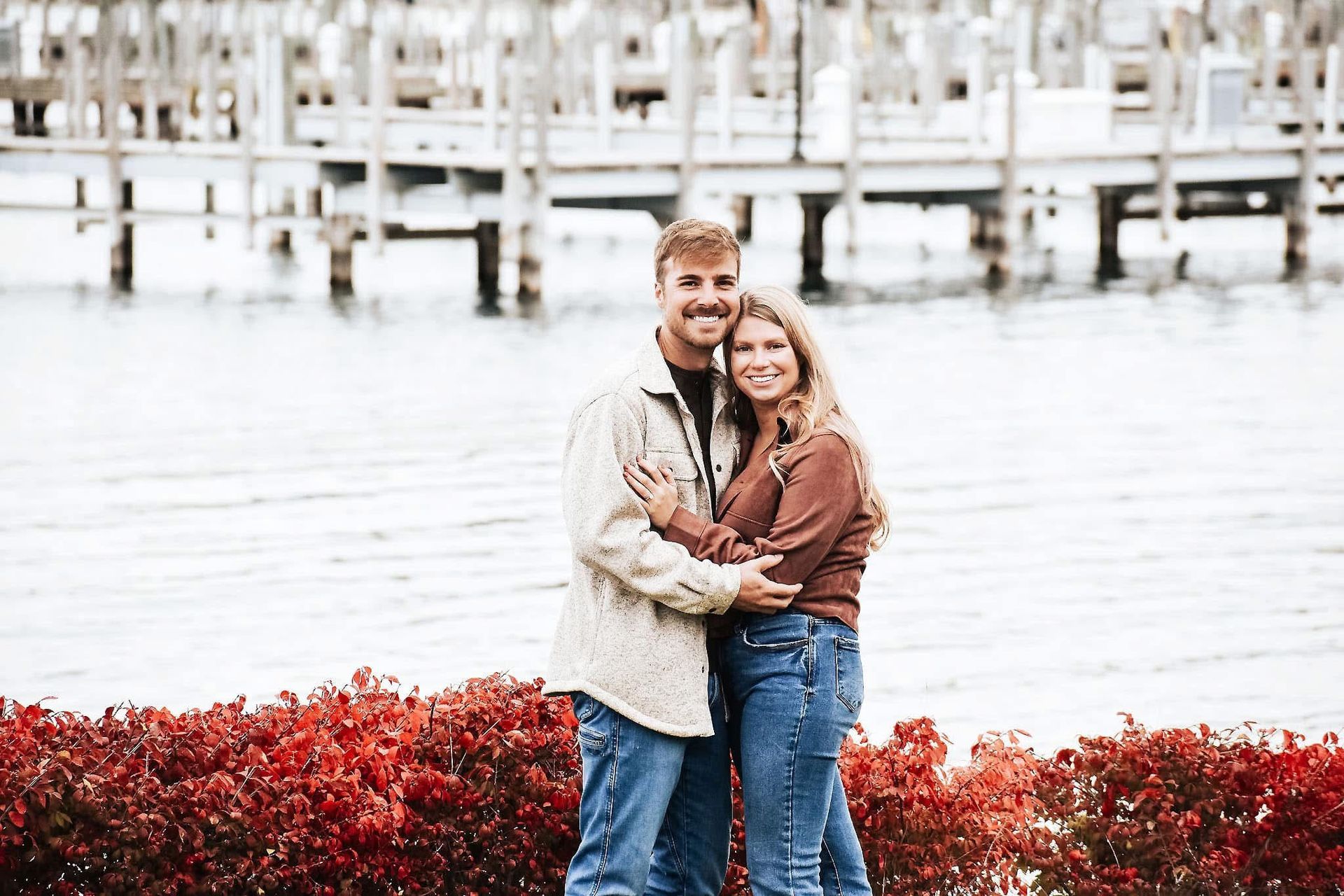 A man and a woman are standing next to each other in front of a body of water.