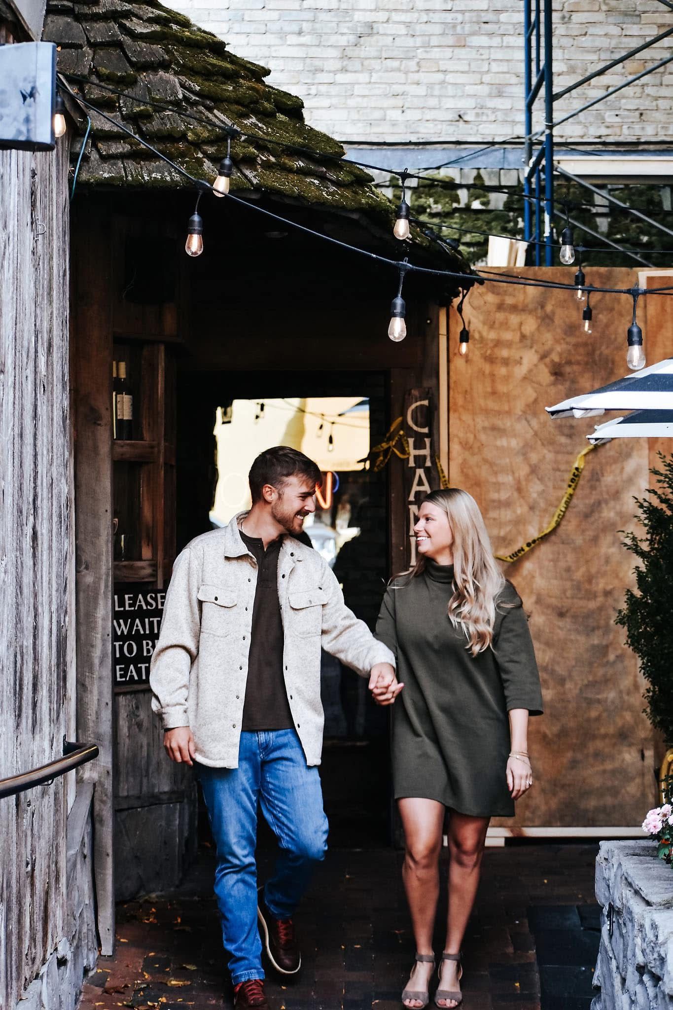 A man and a woman are walking down a sidewalk holding hands.