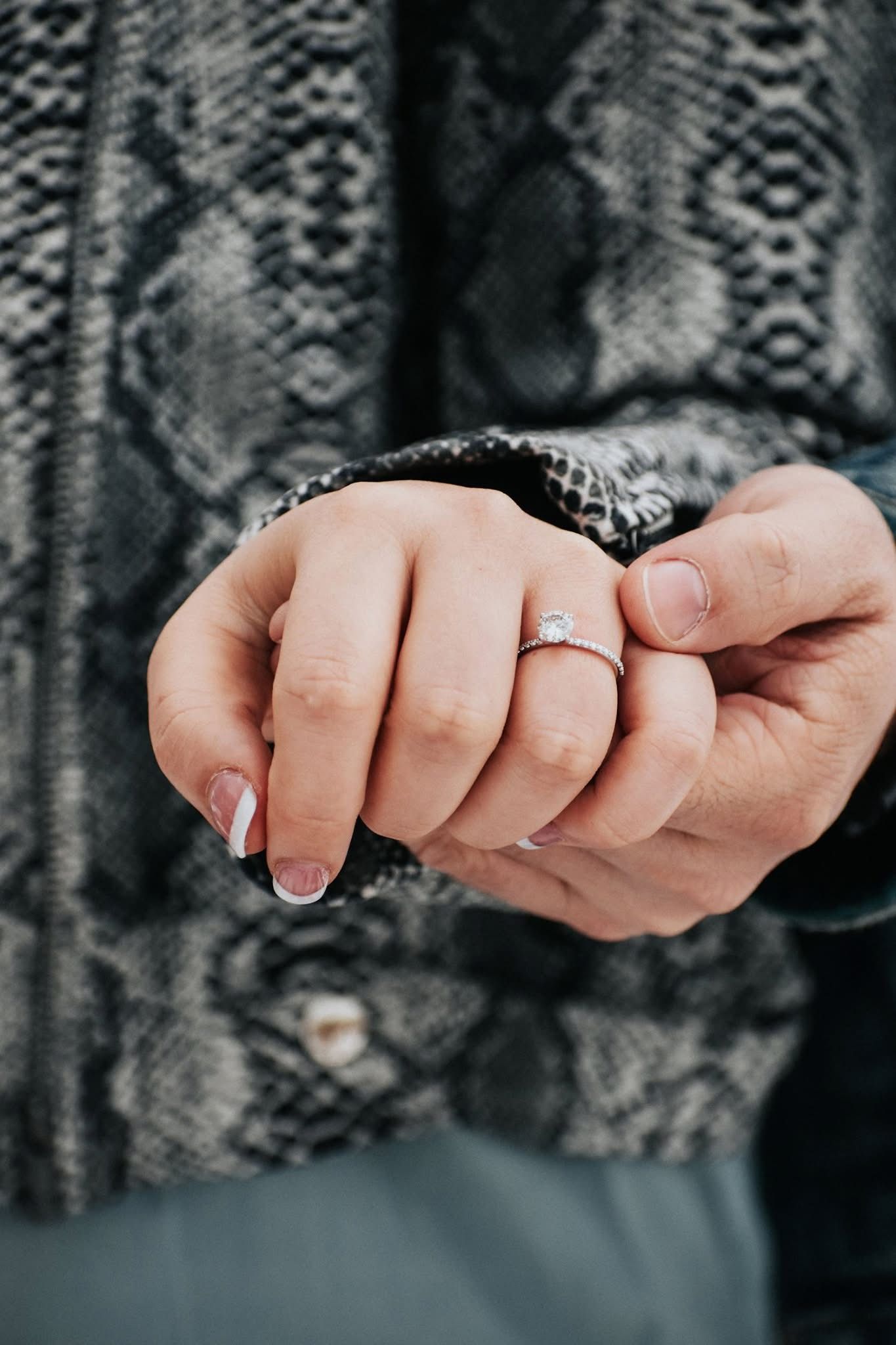 A close up of a person holding another person 's hand with a ring on their finger.