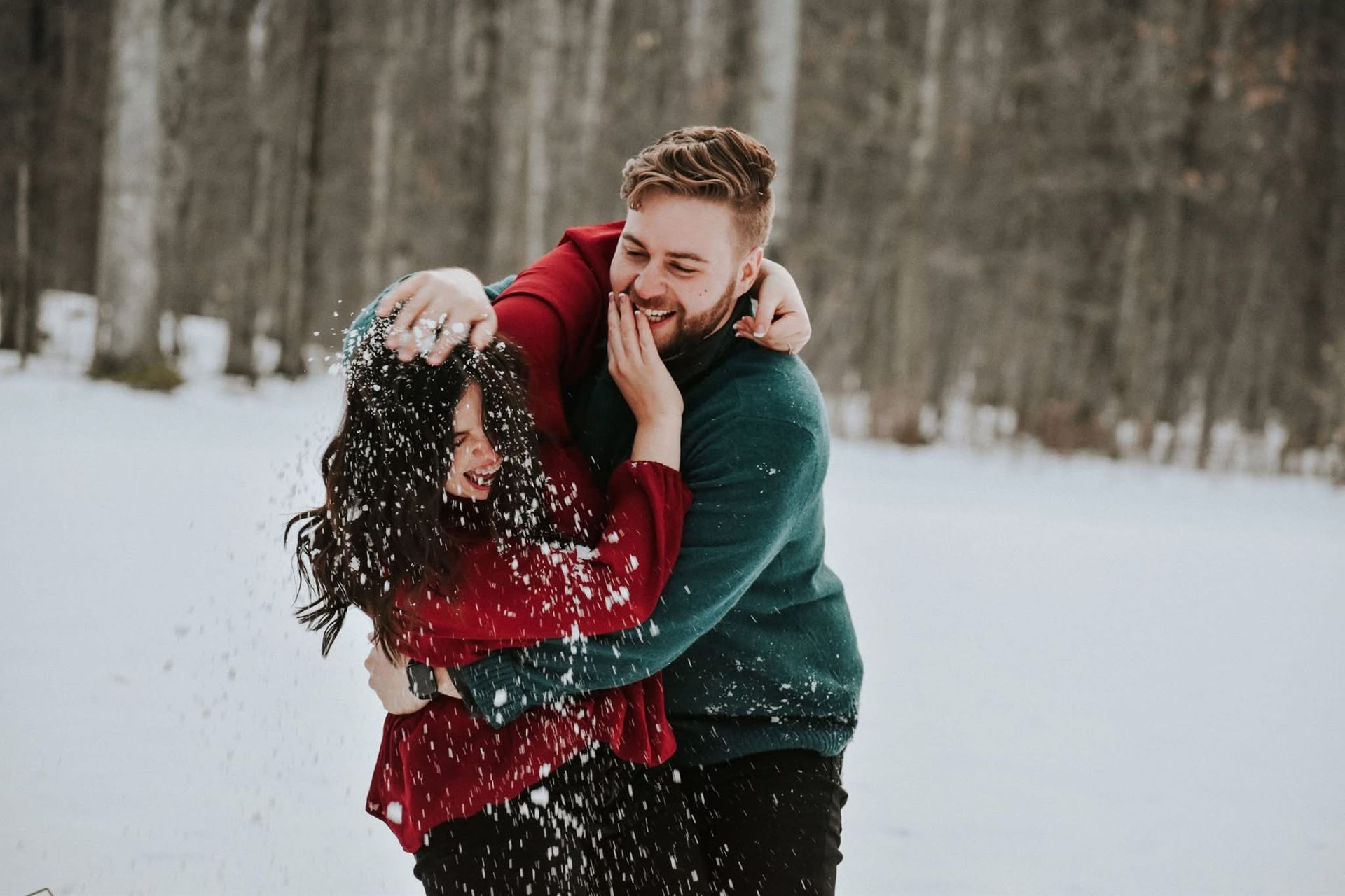 A man and a woman are playing in the snow.