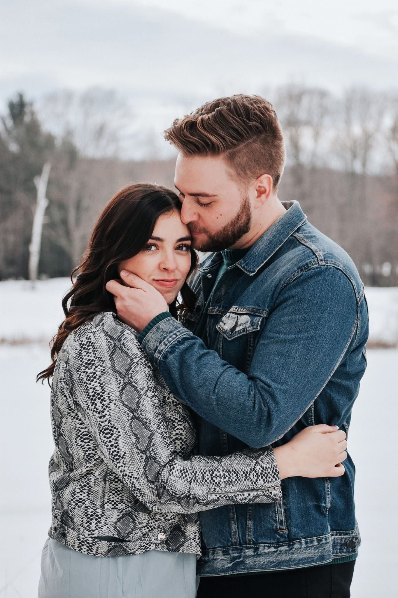 A man is kissing a woman on the forehead in the snow.