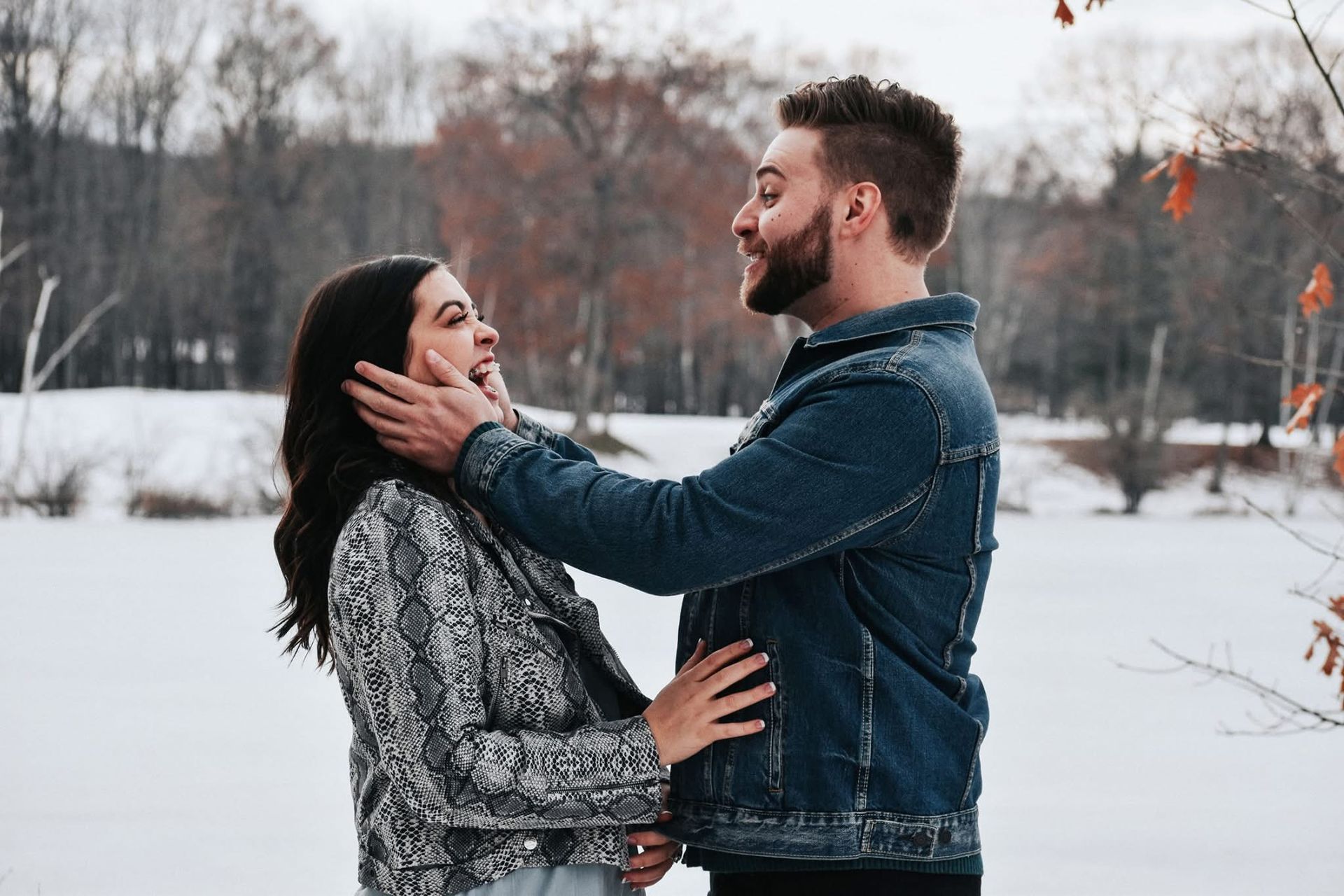 A man and a woman are standing in the snow looking at each other.