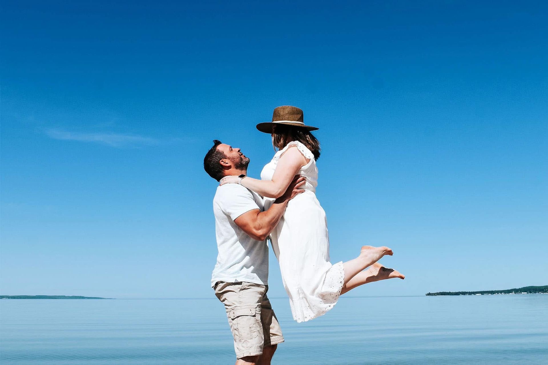A man is holding a woman in his arms on the beach.