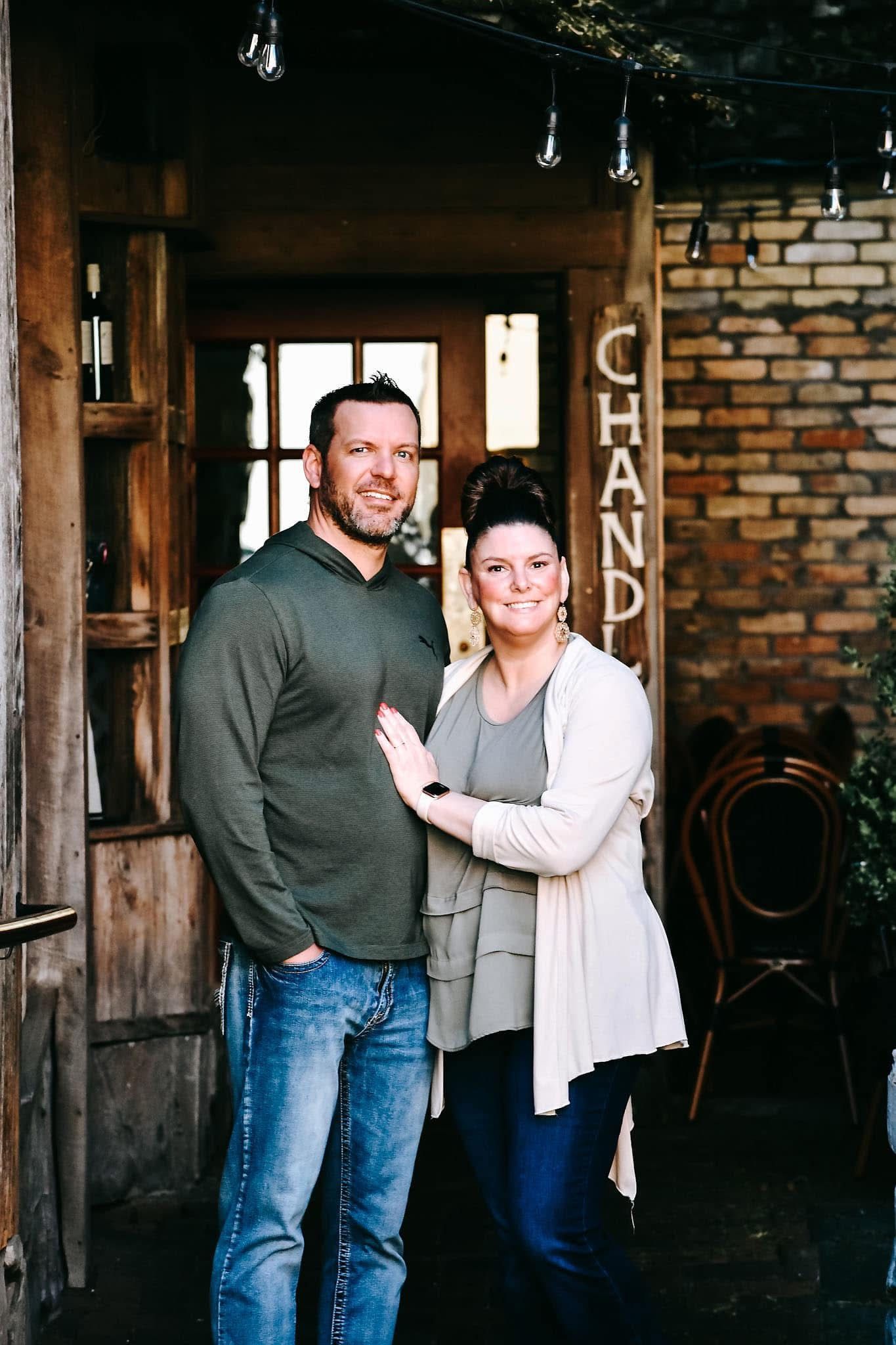 A man and a woman are posing for a picture in front of a brick building.
