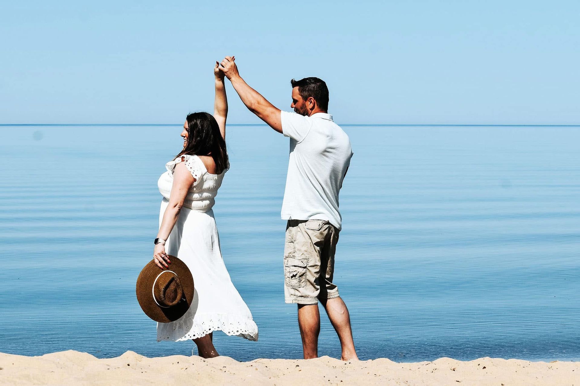A man and a woman are dancing on the beach.