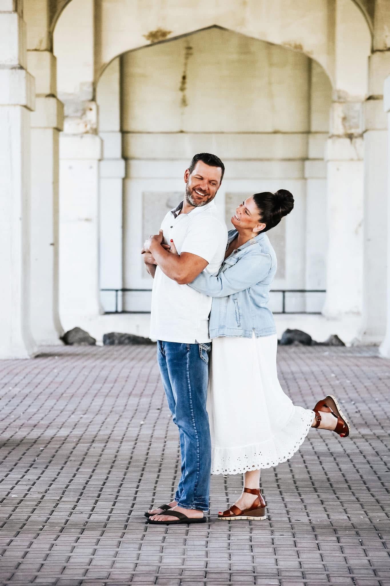 A man is holding a woman in his arms in front of a building.