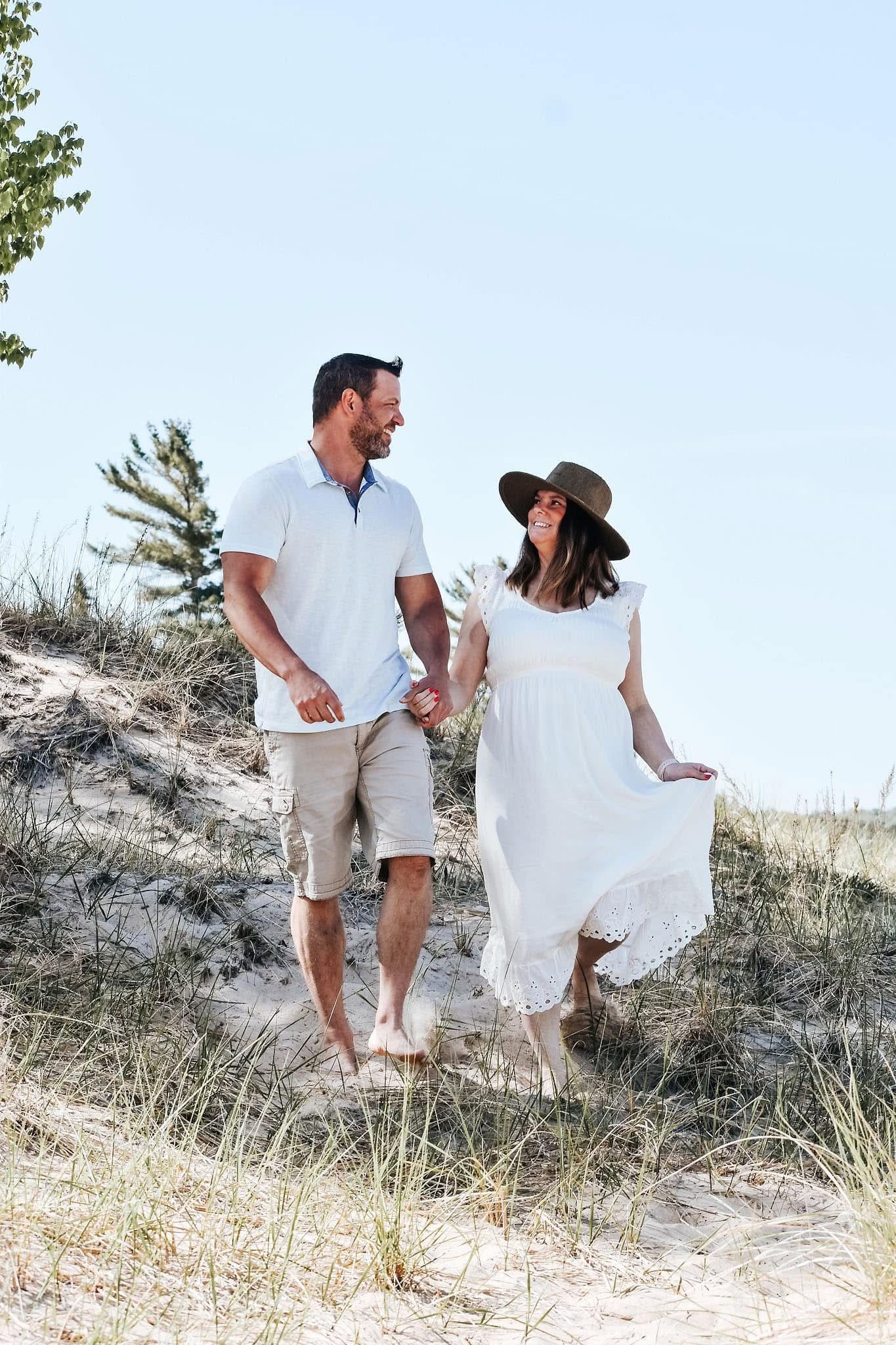 A man and a woman are holding hands while walking on a hill.