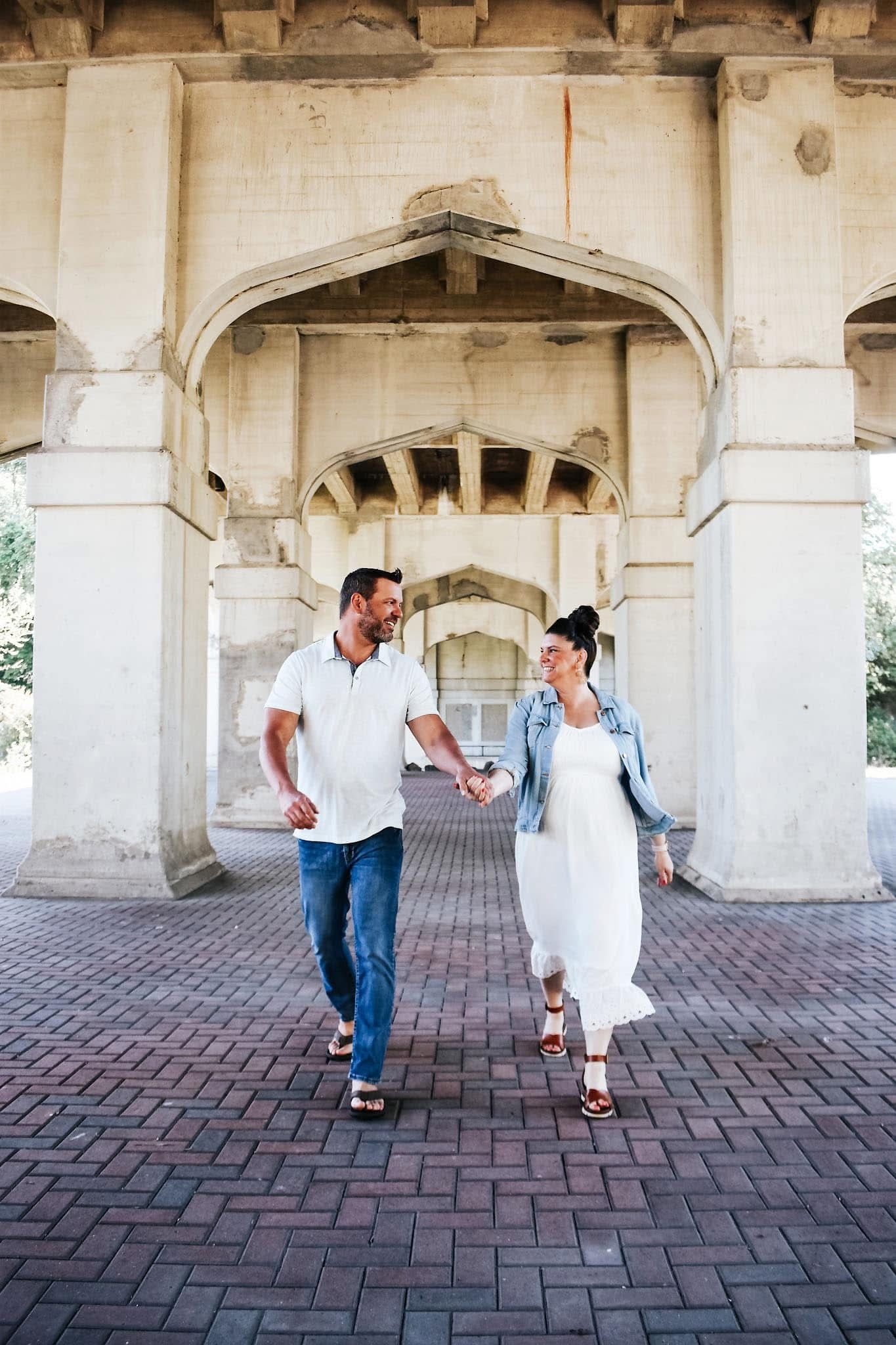 A man and a woman are holding hands and walking in front of a building.