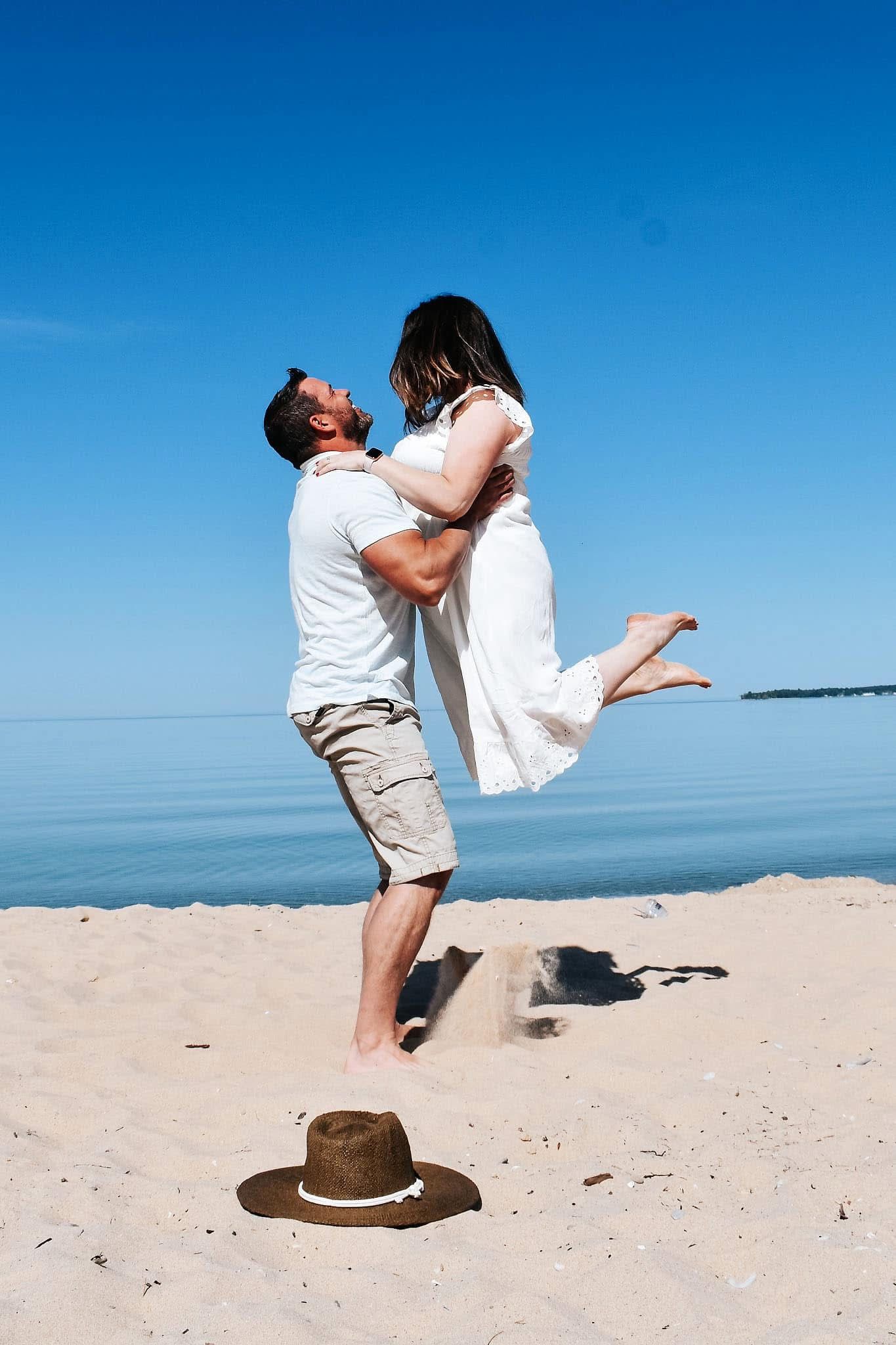 A man is holding a woman in his arms on the beach.
