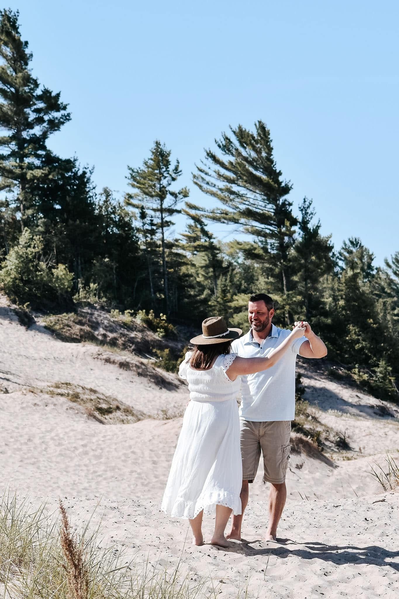 A man and a woman are dancing on a sandy beach.