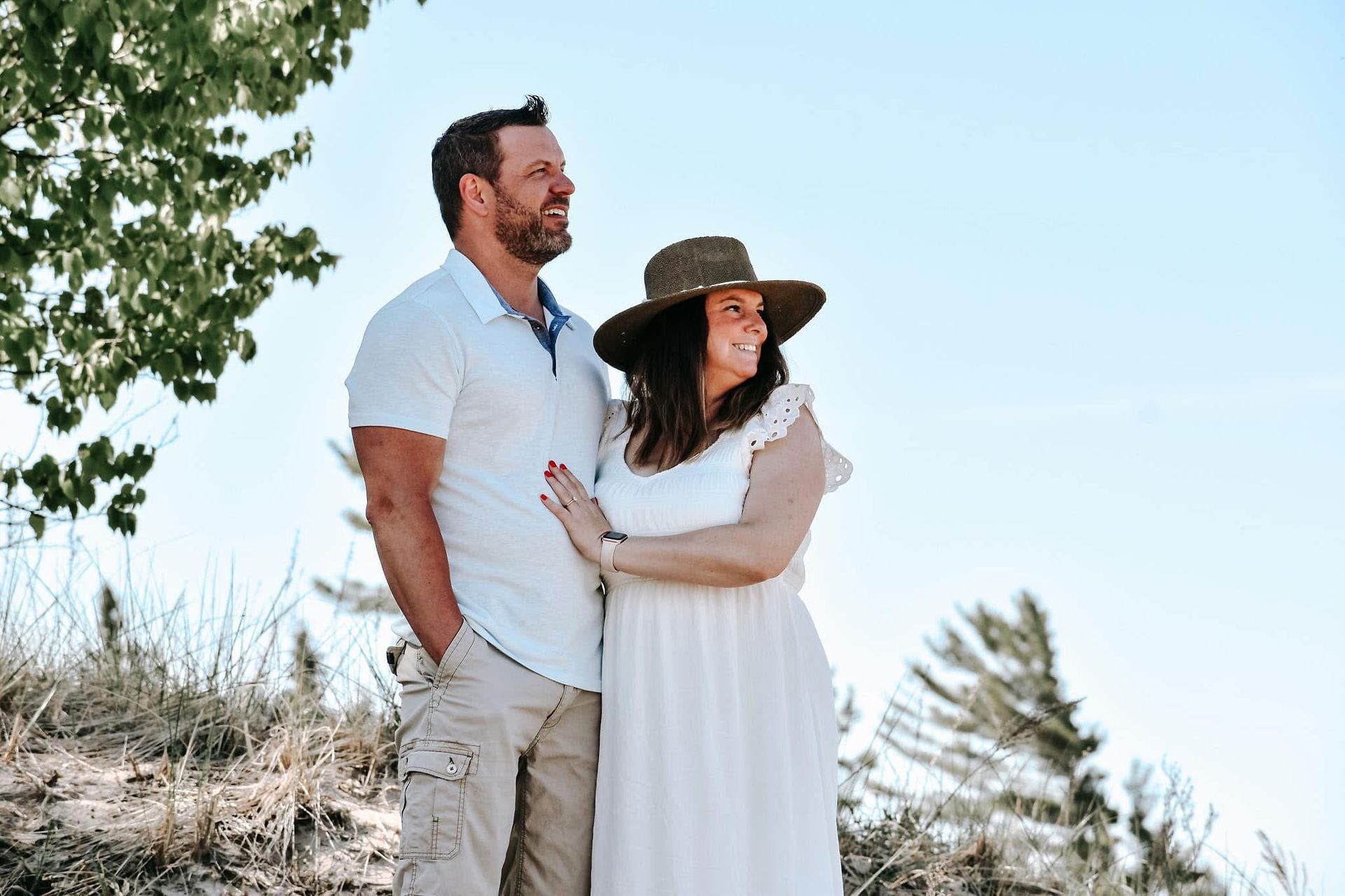 A man and a woman are standing next to each other on top of a hill.