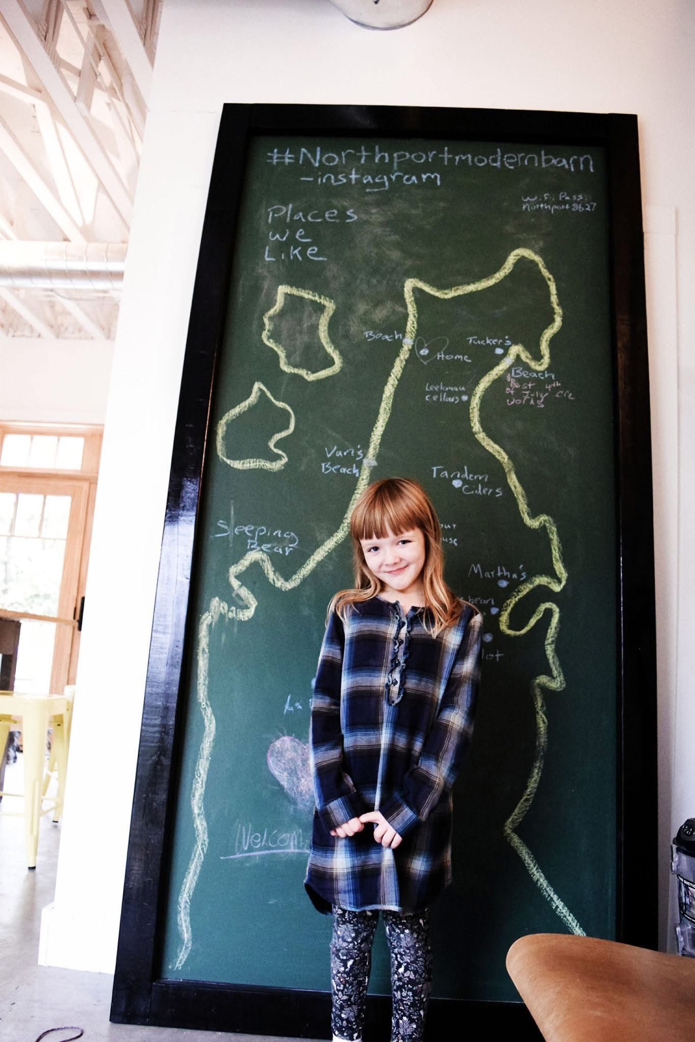 A girl is standing in front of a chalkboard with a map drawn on it
