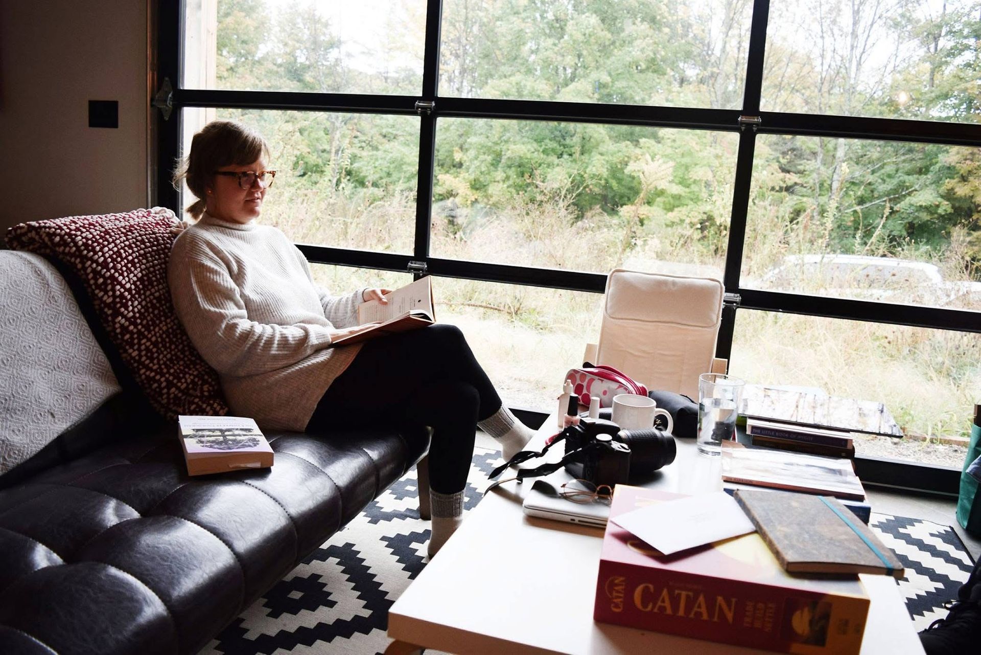 A woman is sitting on a couch reading a book.