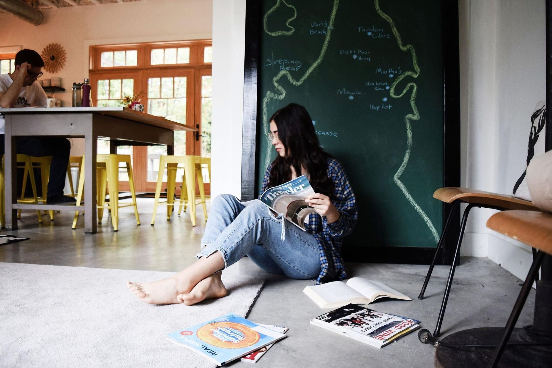 A woman is sitting on the floor reading a book.
