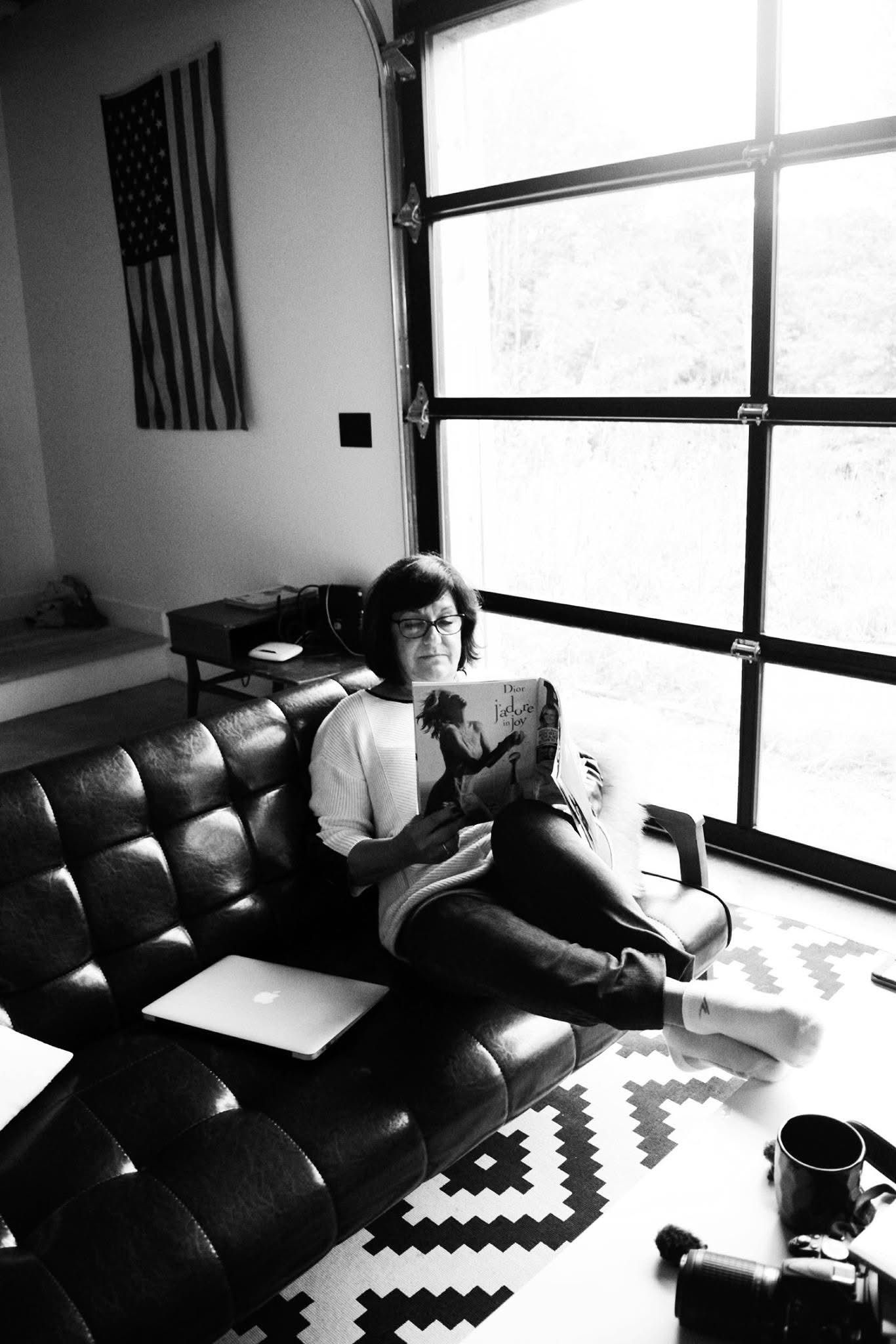 A woman is sitting on a couch reading a book.