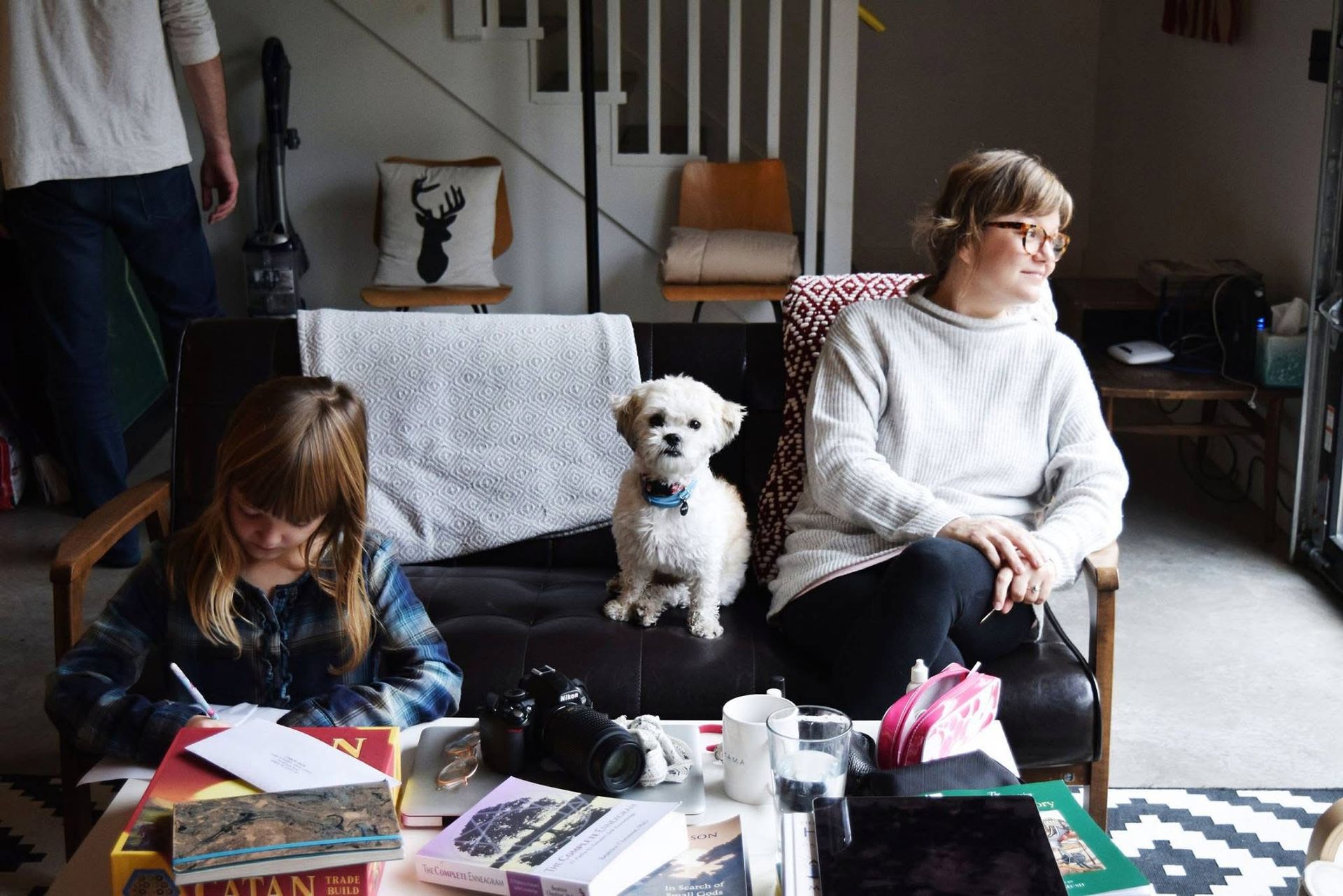 A woman and a child are sitting on a couch with a dog.