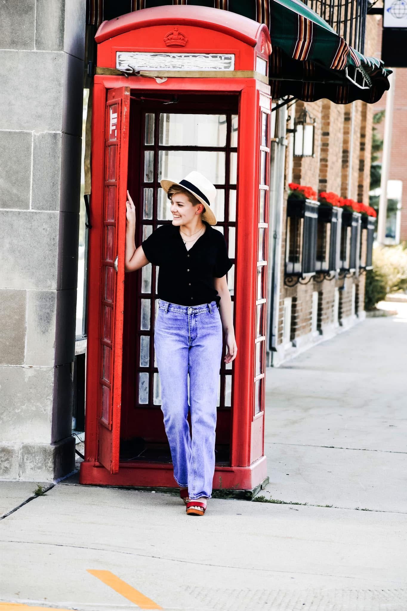 A woman is standing in a red telephone booth