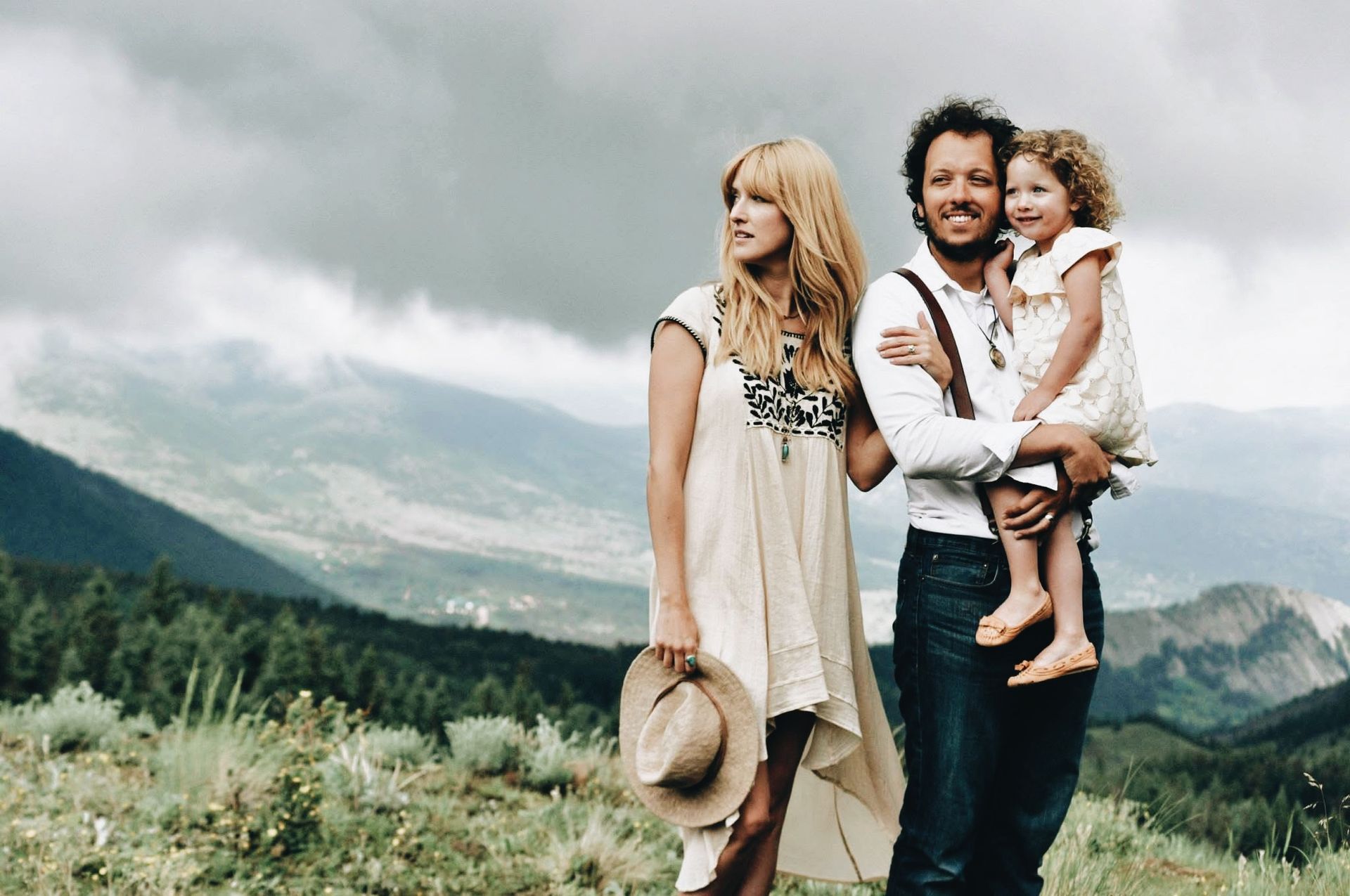 A man and woman are holding a little girl in a field.