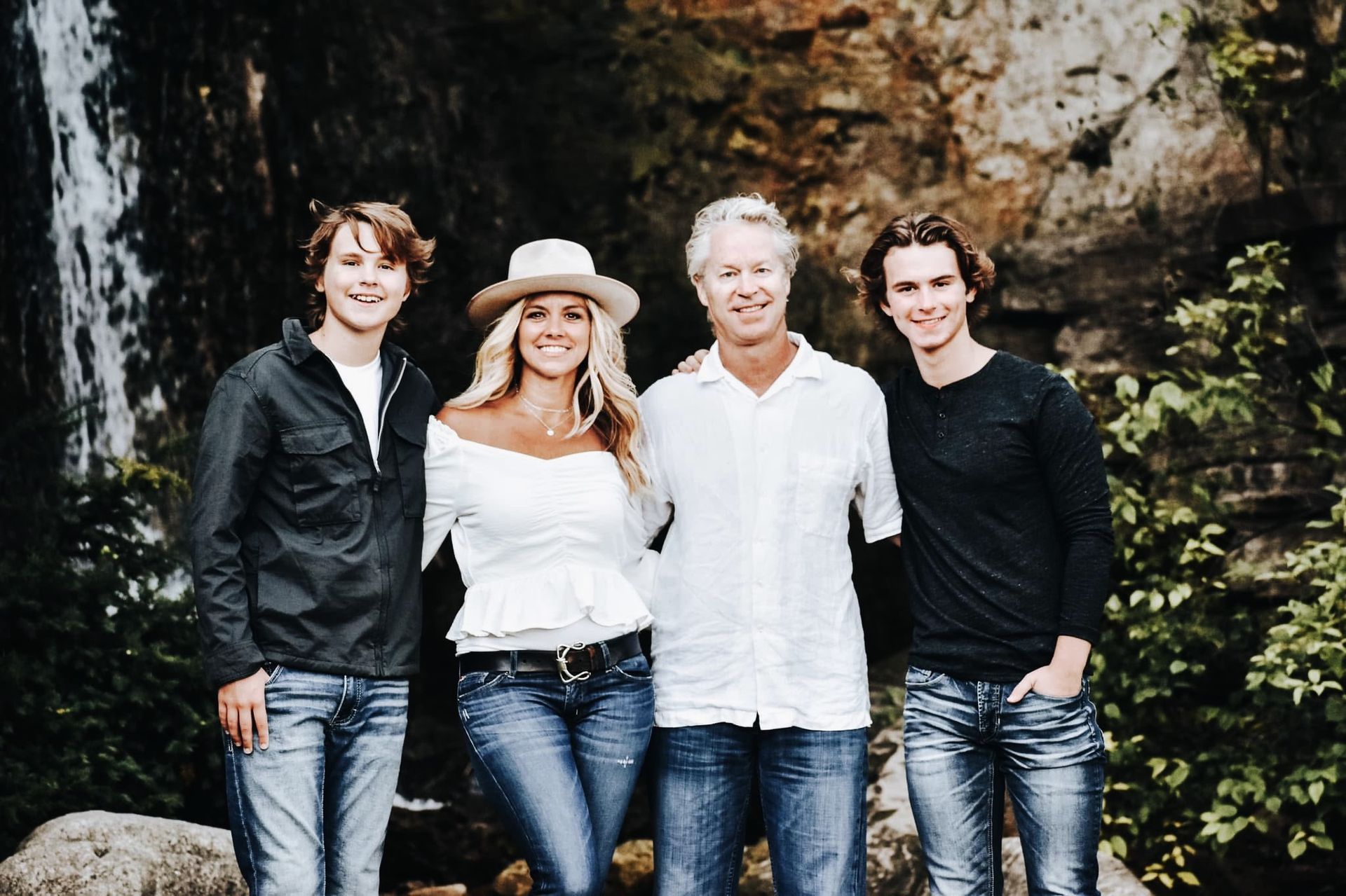 A family posing for a picture in front of a waterfall.