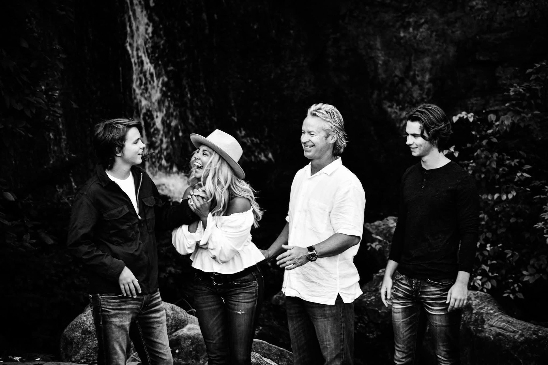 A black and white photo of a family standing next to each other in the woods.