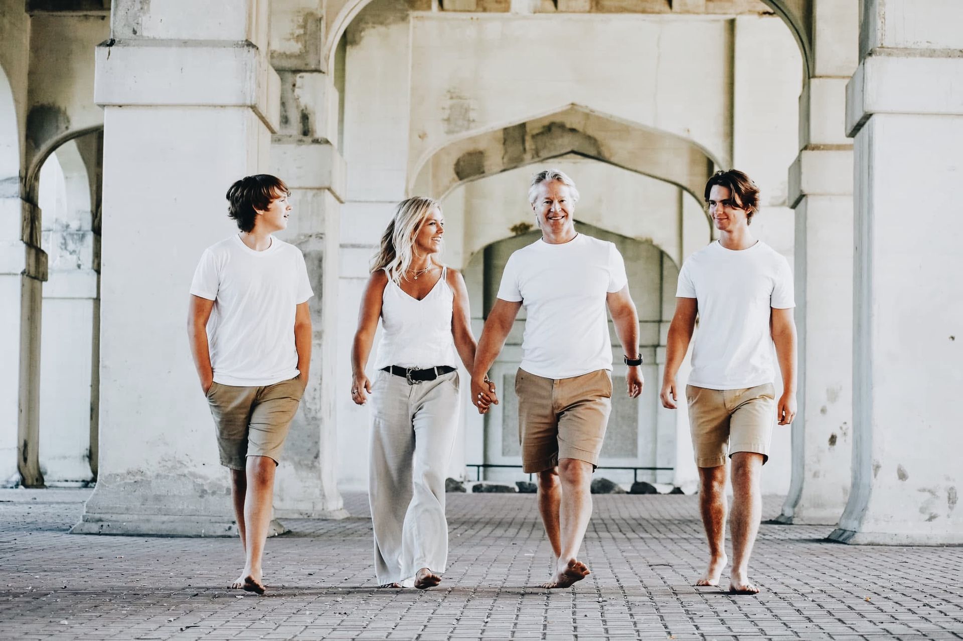 A family is walking under a bridge holding hands.