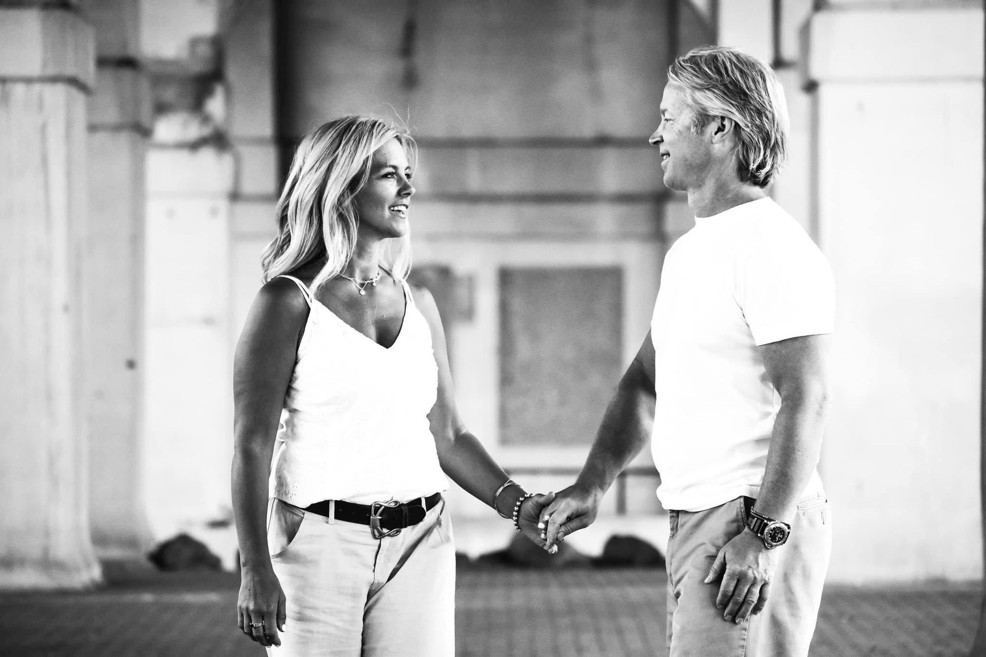 A man and a woman are holding hands in a black and white photo.