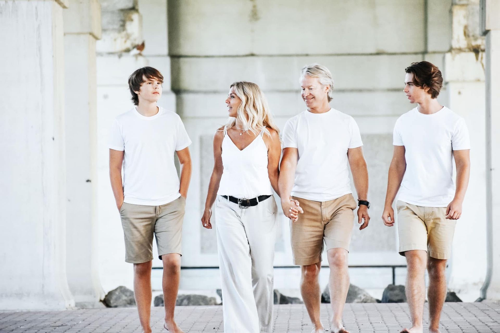 A family is walking down a sidewalk holding hands.