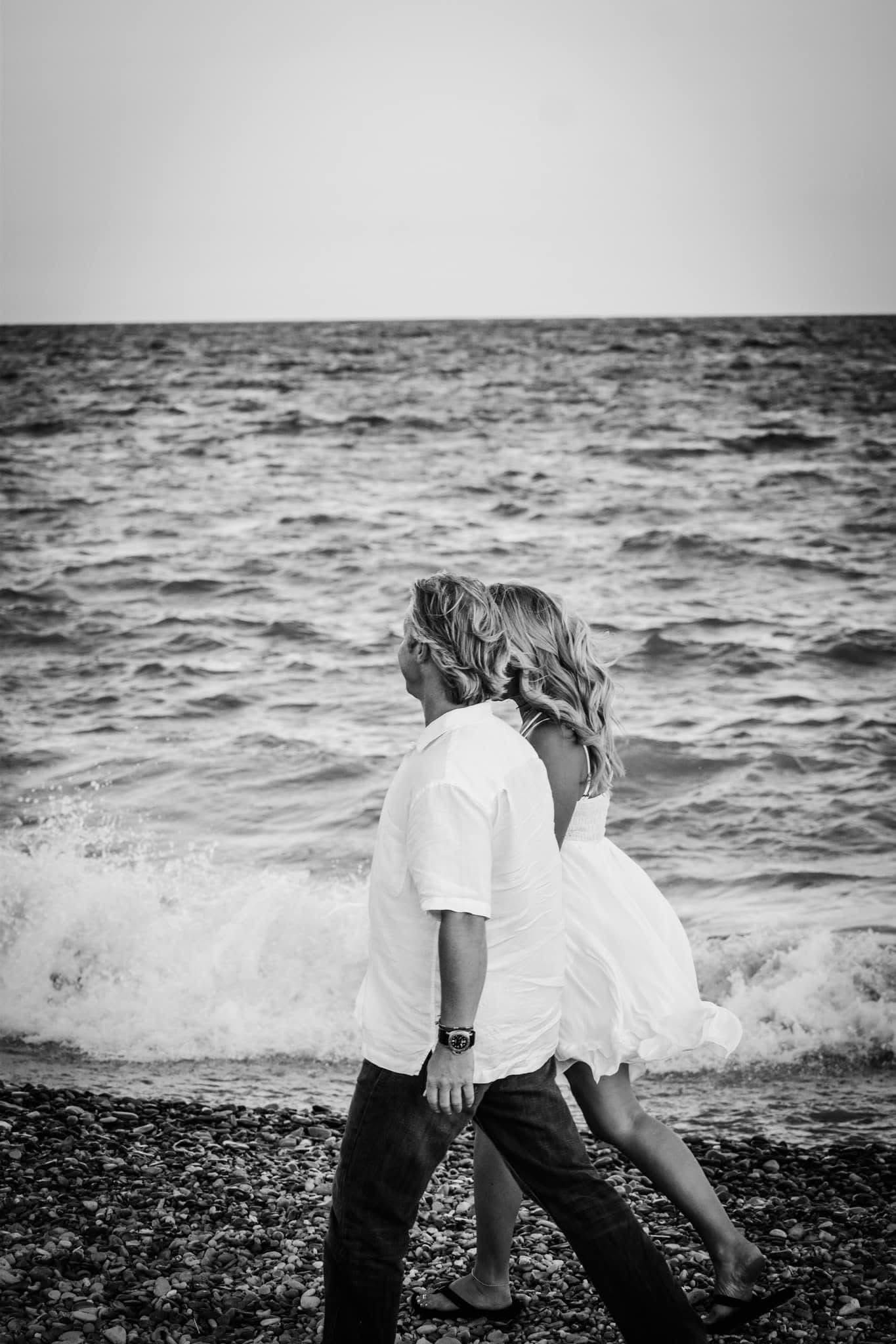 A man and a woman are walking on the beach near the ocean.