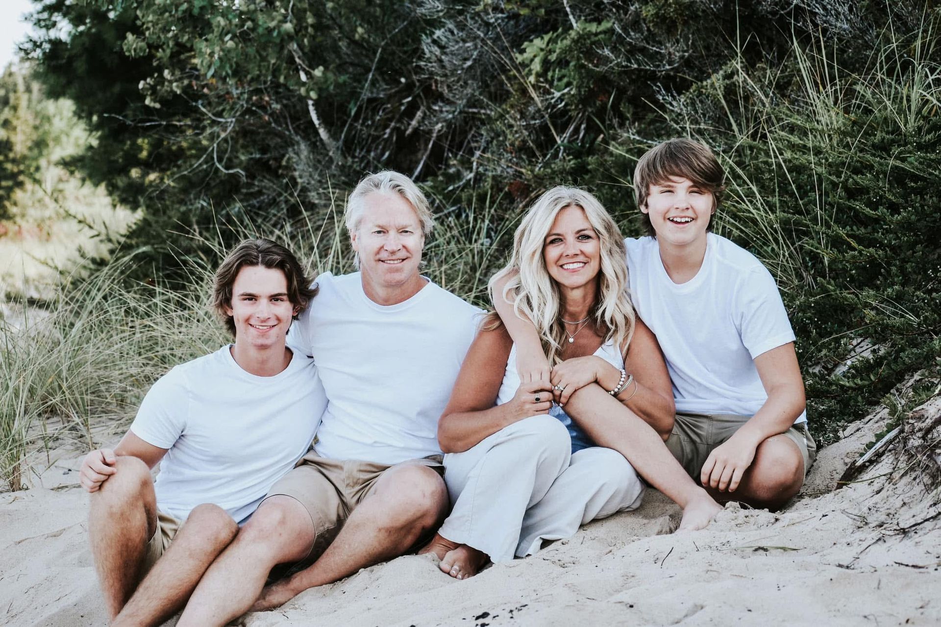 A family posing for a picture while sitting on a sand dune
