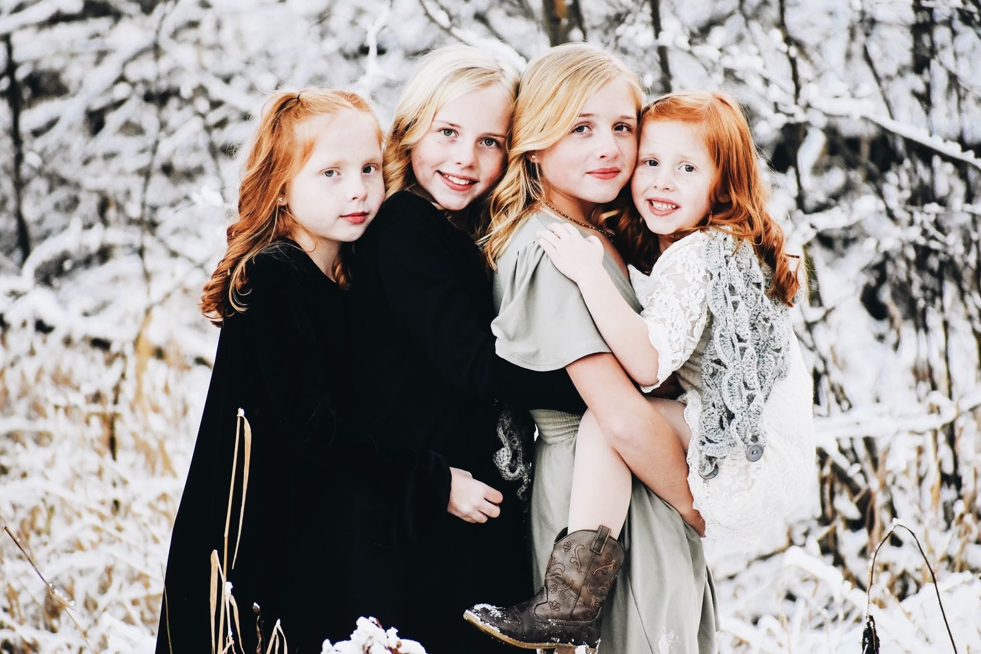 Four little girls are posing for a picture in the snow.