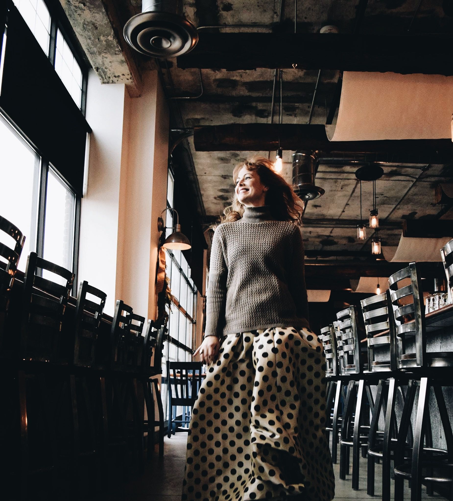 A woman in a polka dot skirt is standing in a restaurant